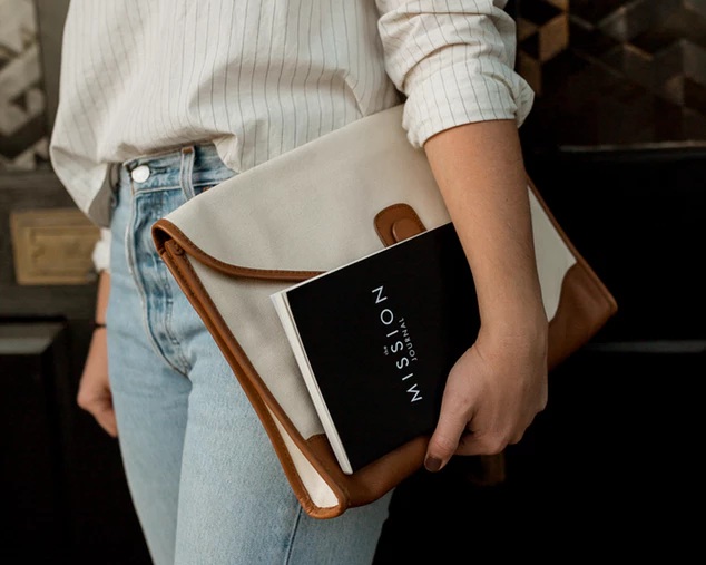 solopreneur carrying a journal and laptop under her arm