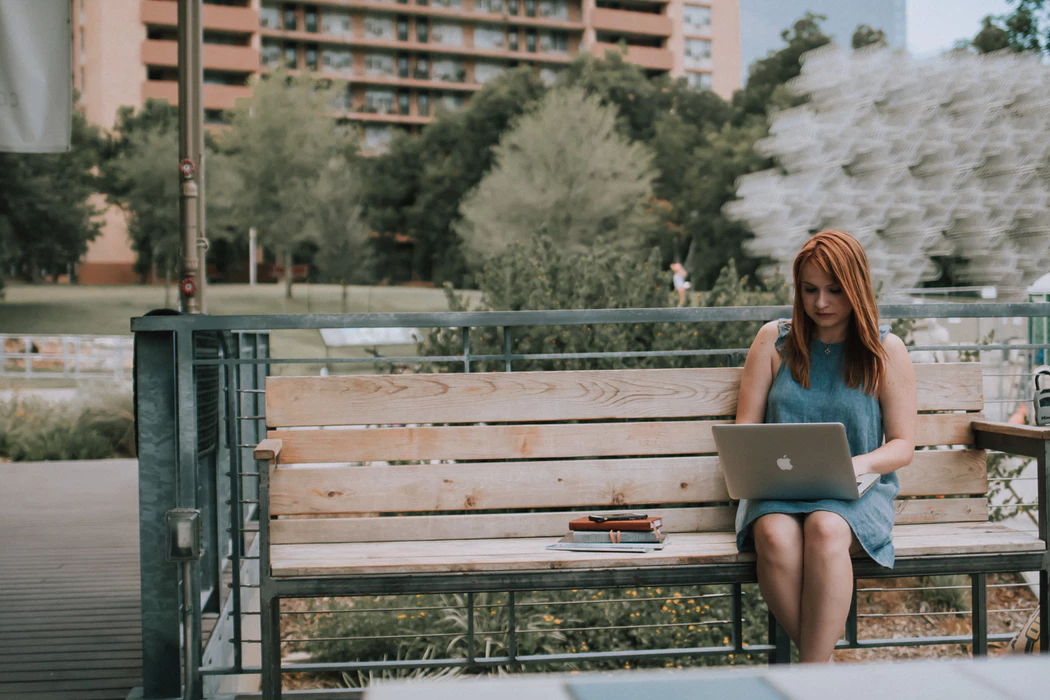 woman using a park bench to remotely manage her business