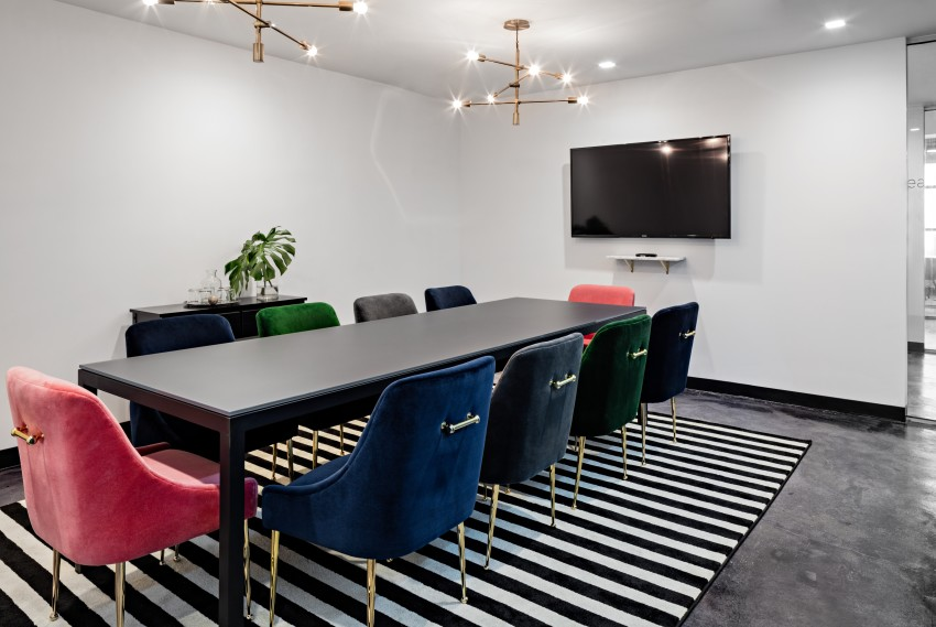 Conference room with long black table and colorful chairs