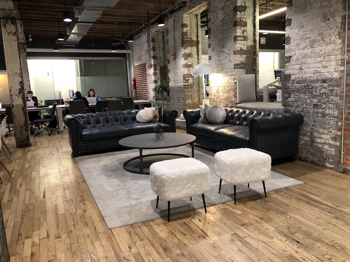 Lounge area with black leather sofas and exposed brick walls