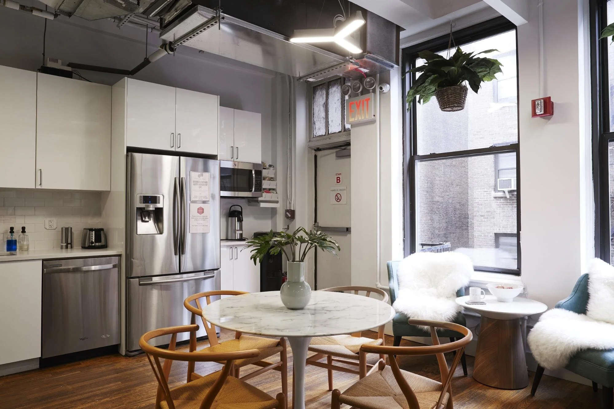 Office kitchen with white cabinets, large window, round table, and chairs