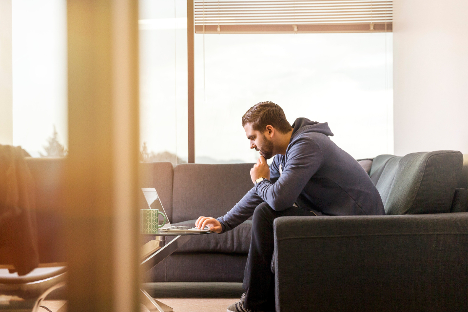 man on couch using laptop