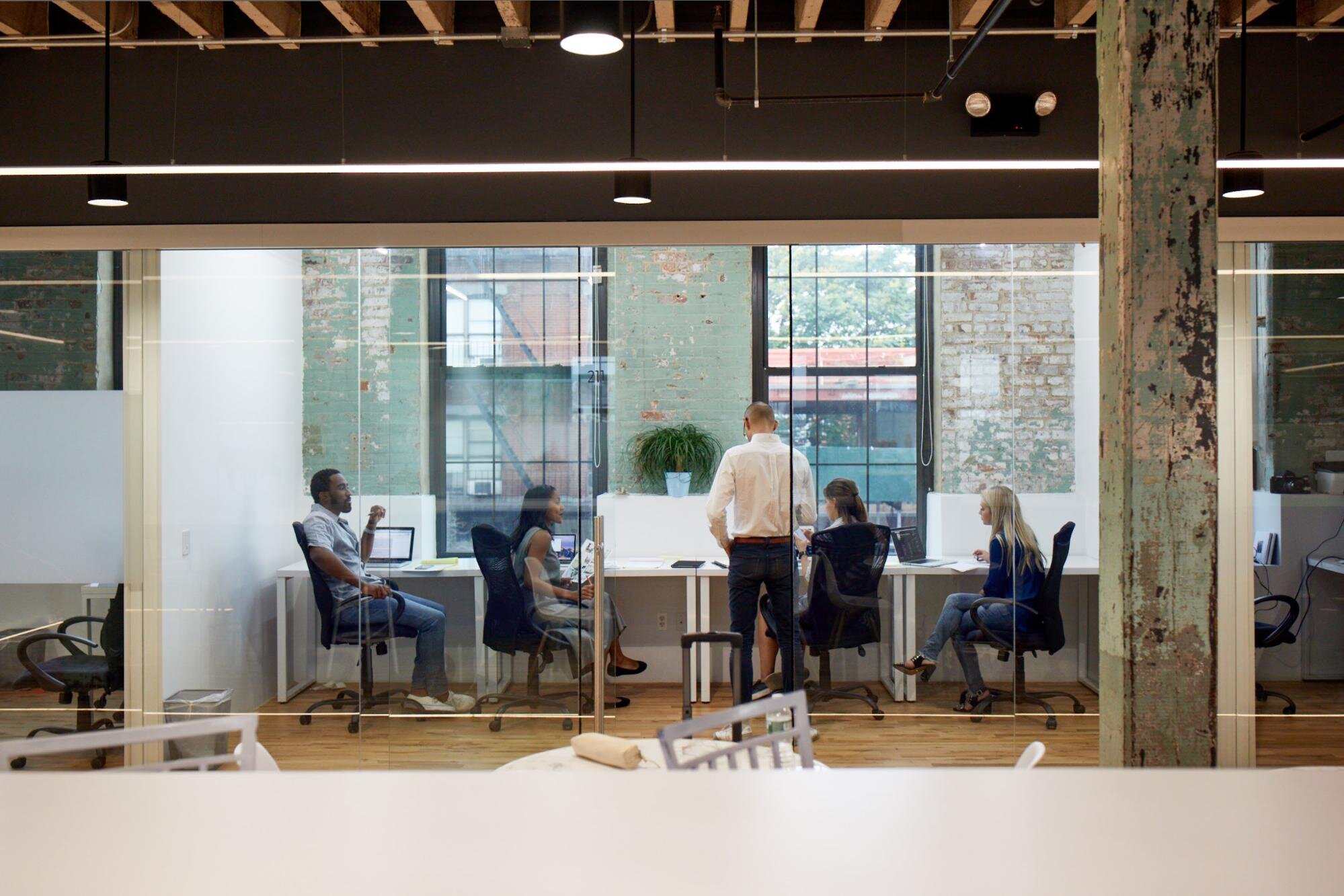 four employees at a shared desk office space