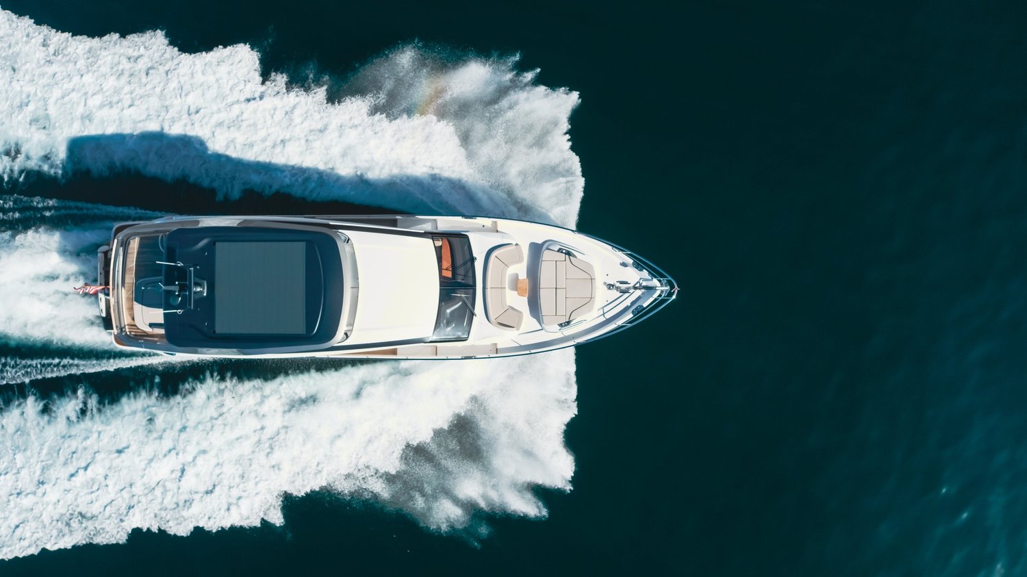 Overhead aerial of yacht cutting through the water