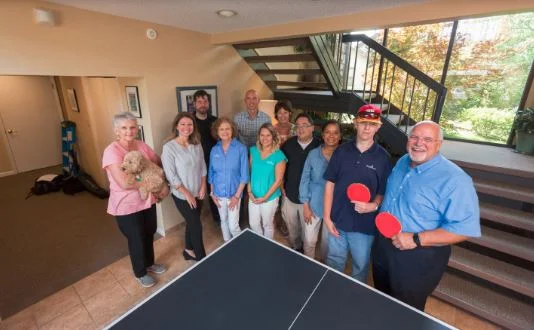  The  Simply Home staff gather around the ping-pong table in the  Simply Home offices. 
