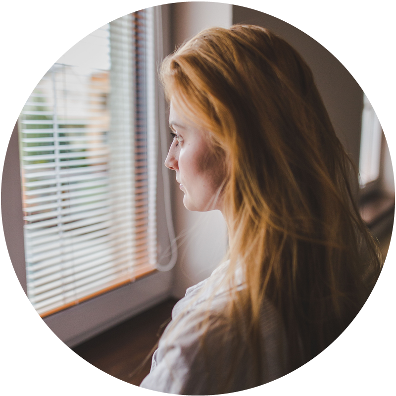 A girl stands at a window and looks out.png
