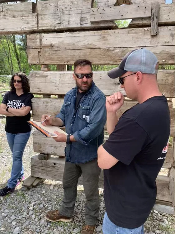 The teams from Barnwood Builders and David’s Vision discuss the plan for David’s log cabin .