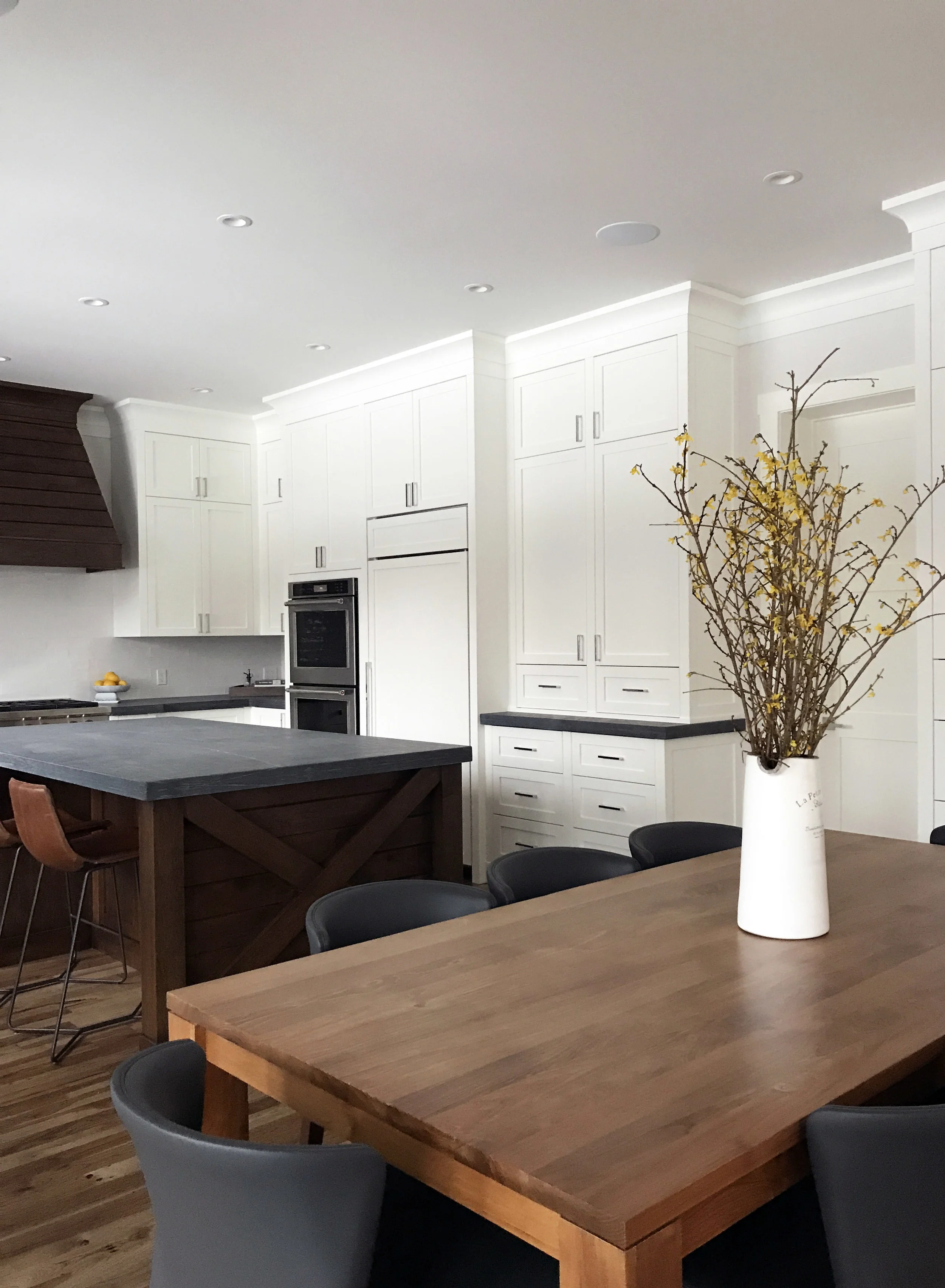 White kitchen with honed counters and warm wood accents. Interior Furnishings by Nyla Free Designs, Build by Veranda Estate Homes