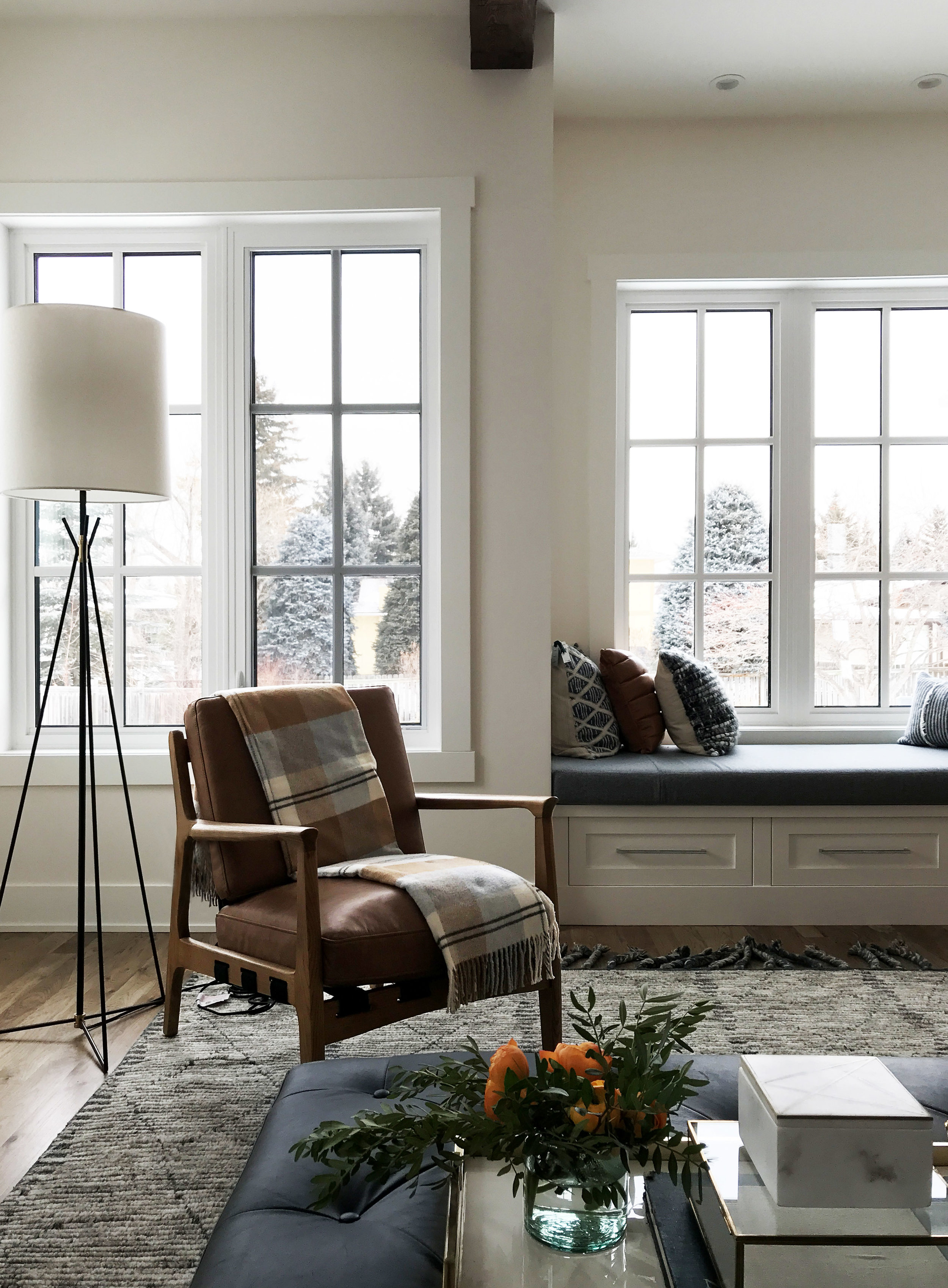Family focused living space with wood beam ceiling detail, window seat and mid-century style accent chair. Interior Design by Nyla Free Designs, Build by Veranda Estate Homes
