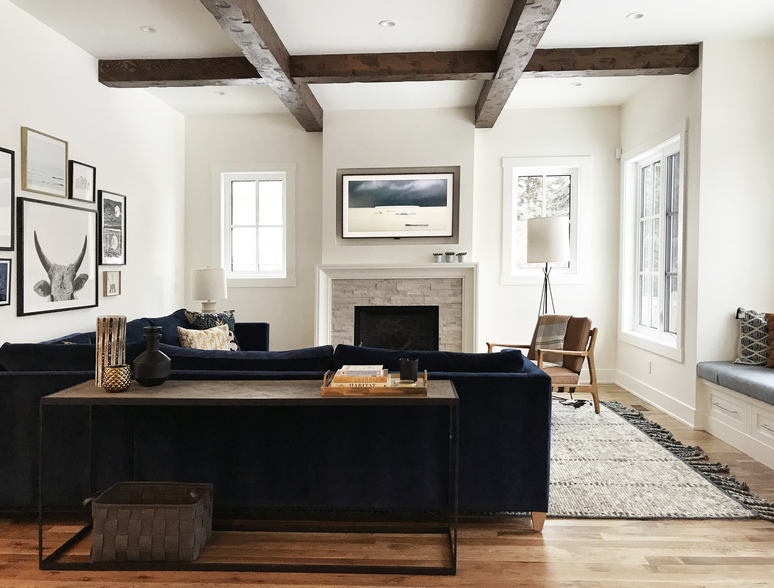 Family focused living space with wood beam ceiling detail and navy chenille sectional. Interior Design by Nyla Free Designs, Build by Veranda Estate Homes