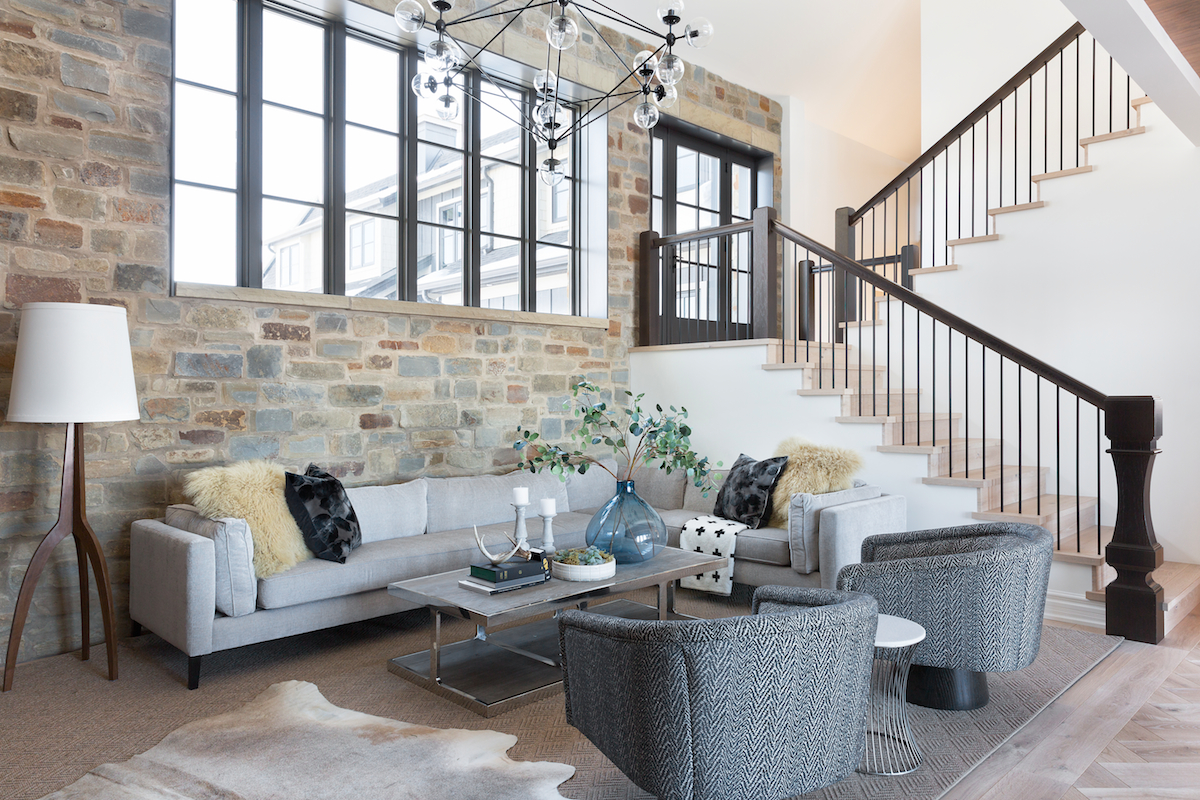 A Living Room with feature stone wall, layered carpets and custom furniture from a Rural Alberta Country House, Interior Design by Calgary Design Studio Nyla Free Designs Inc, Architecture: Dejong Design Associates, Photography: Phil Crozier #calgaryinteriordesign #calgaryinteriordesigner #nylafreedesigns #livingessentials #countryhouse