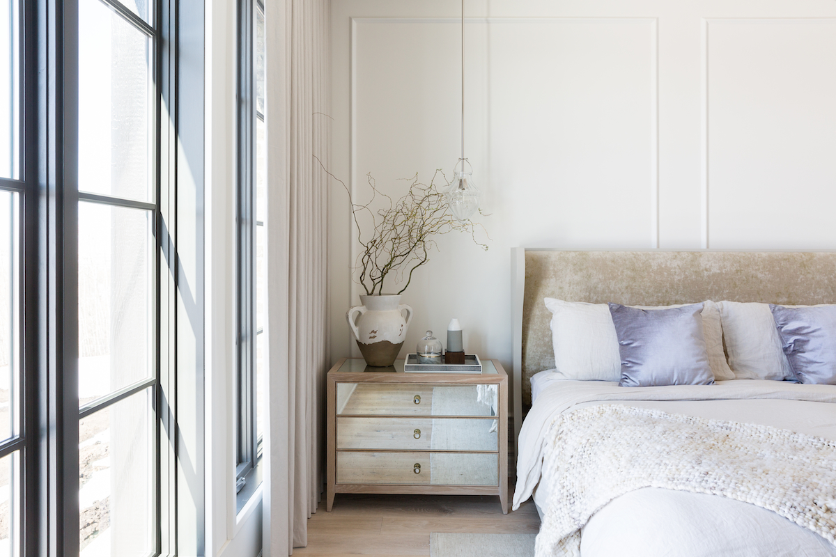 The neutral, light and airy master bedroom with wall panelling and pendant light from a Rural Alberta Country House, Interior Design by Calgary Design Studio Nyla Free Designs Inc, Photography: Phil Crozier #calgaryinteriordesign #calgaryinteriordesigner #nylafreedesigns #masterbedroominspirations #countryhouse