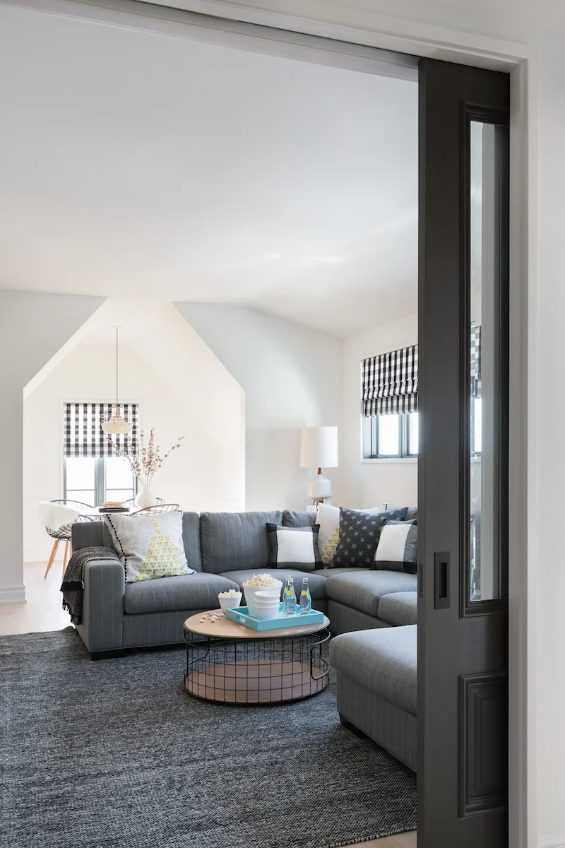 The Media room onlooking craft room (behind) Pitched roof line and plenty of lounging space from a Rural Alberta Country House, Interior Design by Calgary Design Studio Nyla Free Designs Inc, Architecture: Dejong Design Associates, Photography: Phil Crozier #calgaryinteriordesign #calgaryinteriordesigner #nylafreedesigns #mediaroominspirations #countryhouse