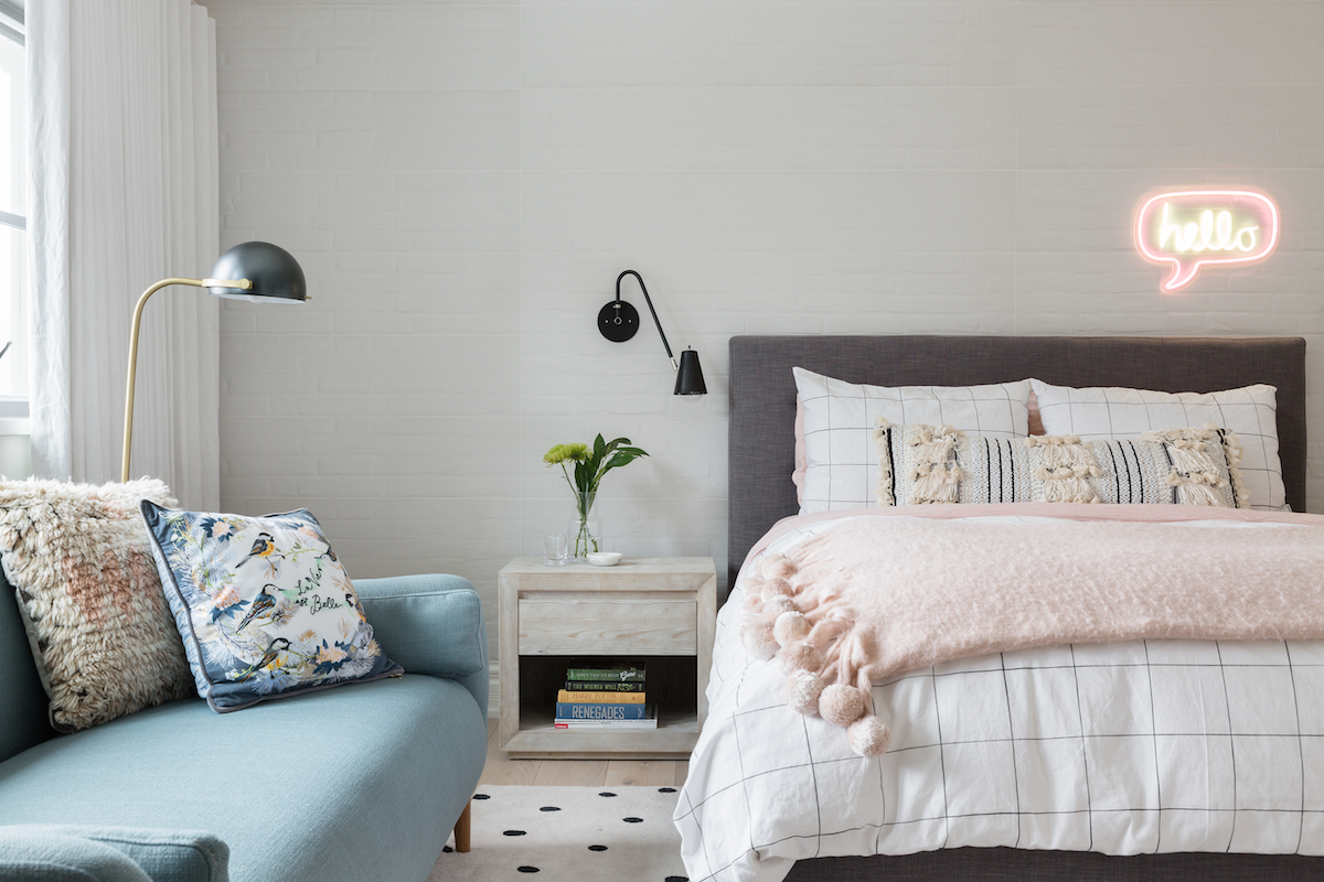 The girls bedroom with white brick tile feature wall, teal sofa and wall sconces either side of bed frame, with “hello” neon sign from a Rural Alberta Country House, Interior Design by Calgary Design Studio Nyla Free Designs Inc, Photography: Phil Crozier #calgaryinteriordesign #calgaryinteriordesigner #nylafreedesigns #girlsbedroominspirations #countryhouse