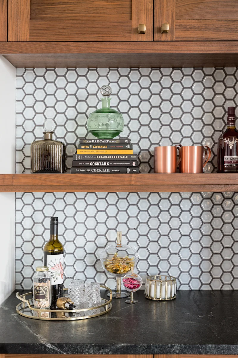 The Bar area with walnut cabinetry with hexagon backsplash, styled with decanters from a Rural Alberta Country House, Interior Design by Calgary Design Studio Nyla Free Designs Inc, Photography: Phil Crozier #calgaryinteriordesign #calgaryinteriordesigner #nylafreedesigns #sittingroominspirations #countryhouse