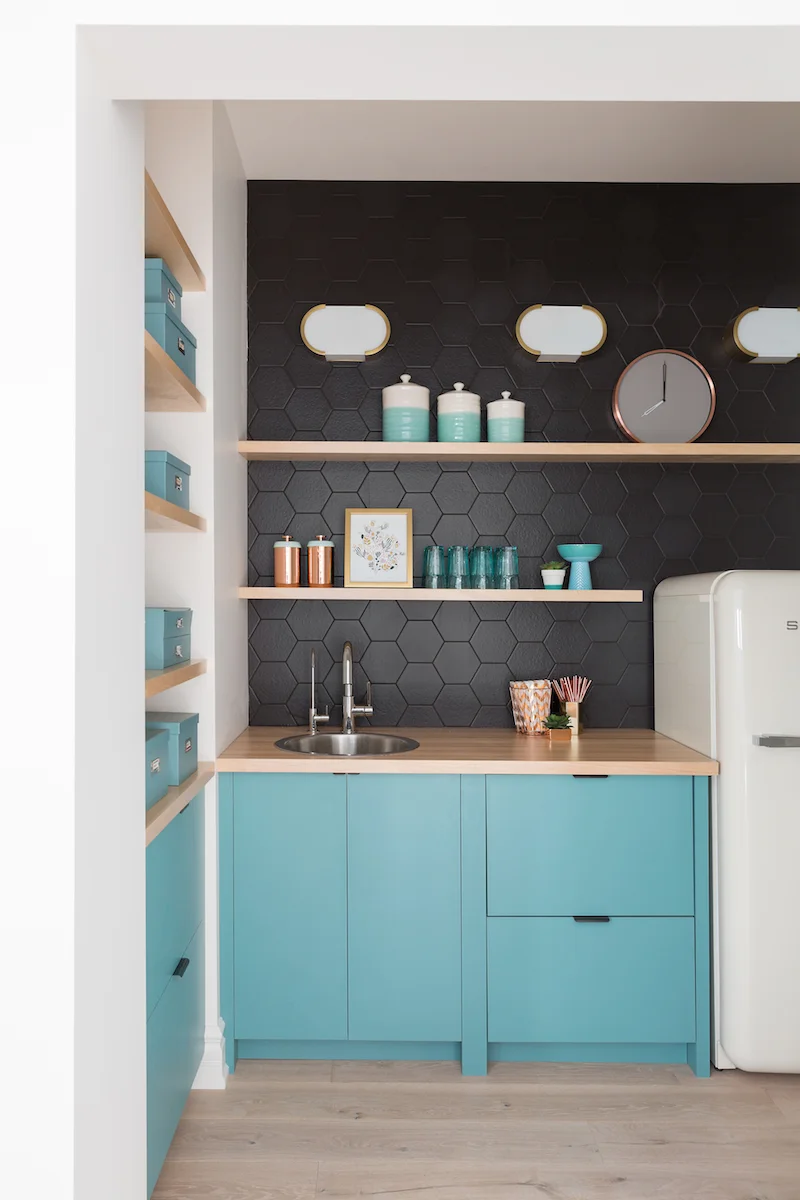The retro bar with turquoise cabinetry, smeg fridge large black hex backsplash tile and open shelving from a Rural Alberta Country House, Interior Design by Calgary Design Studio Nyla Free Designs Inc, Photography: Phil Crozier #calgaryinteriordesign #calgaryinteriordesigner #nylafreedesigns #wetbarinspirations #countryhouse