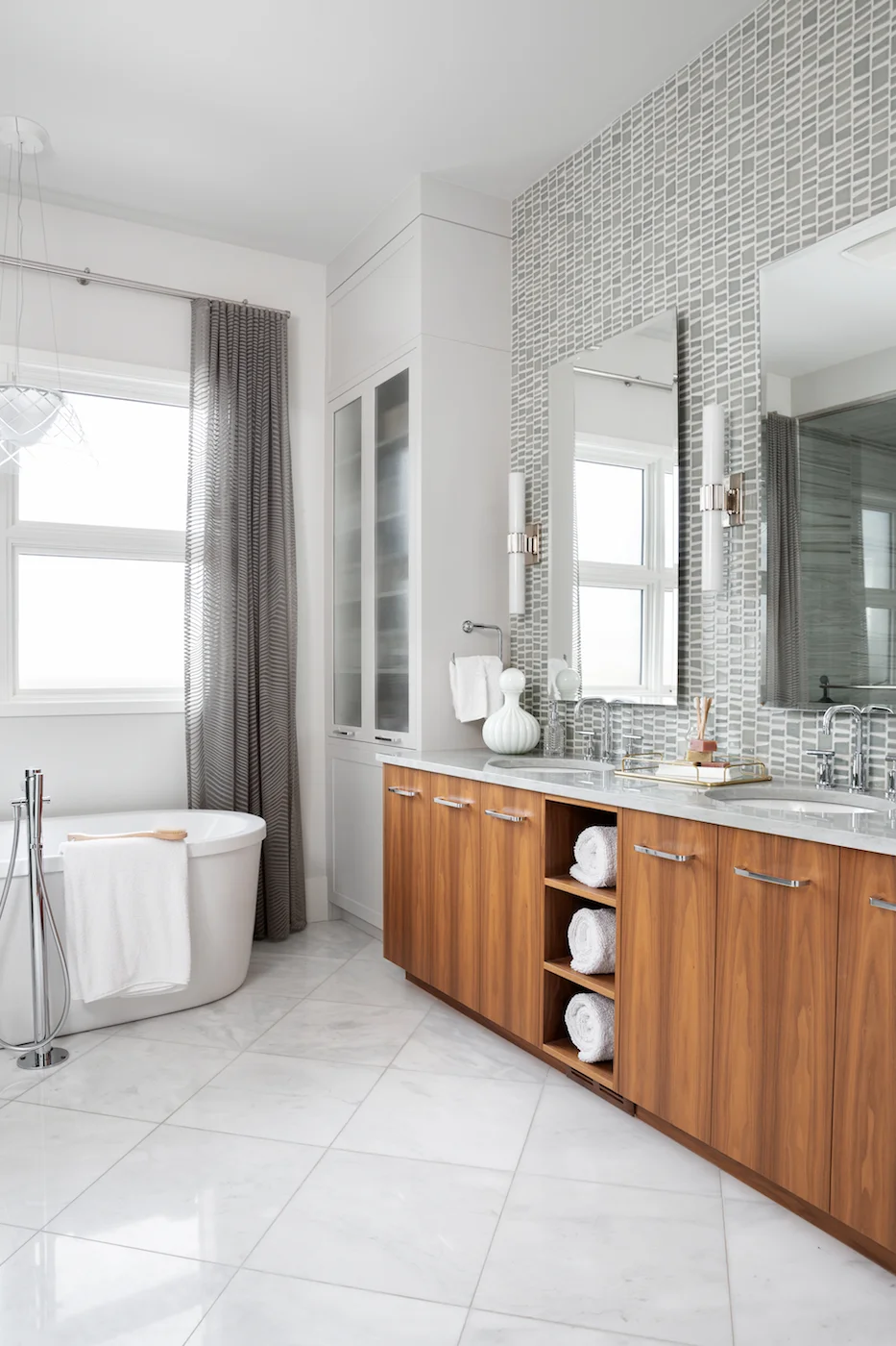 The master ensuite featuring glass tile backsplash, white marble tile floors, walnut vanity and free-standing soaker tub from an Elbow Park Residence, Interior Design by Calgary Design Studio: Nyla Free Designs, Photography: Phil Crozier #nylafreede