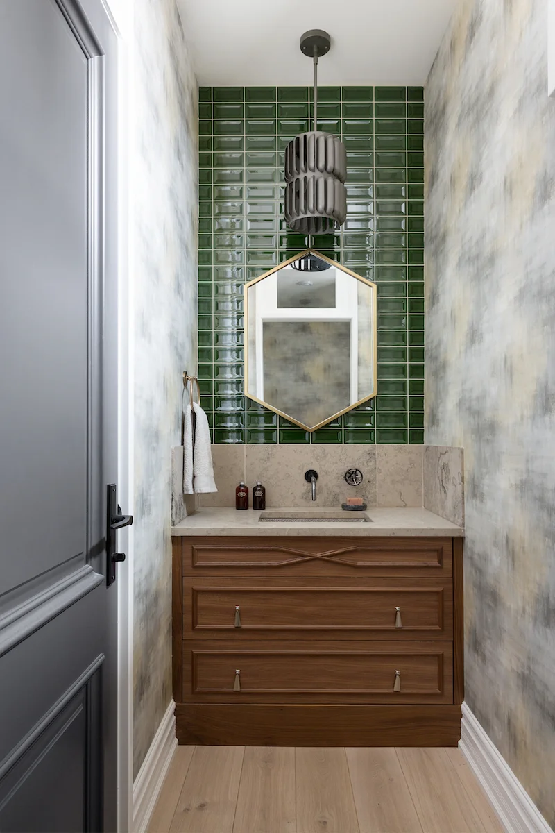 The powder room with Kelly green subway tile backsplash, limestone counters, and hammered sink from a Rural Alberta Country House, Interior Design by Calgary Design Studio Nyla Free Designs Inc, Photography: Phil Crozier #calgaryinteriordesign #calgaryinteriordesigner #nylafreedesigns #powderroominspirations #countryhouse