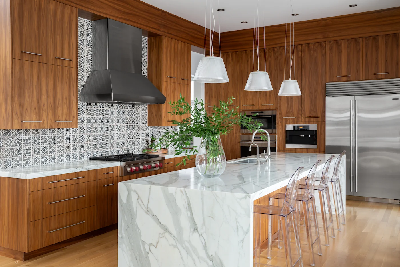 The kitchen, with walnut cabinetry, louis ghost counter stools, handmade ceramic tile backsplash and white marble waterfall countertop from an Elbow Park Residence, Interior Design by Calgary Design Studio: Nyla Free Designs, Photography: Phil Crozier #nylafreedesigns #nfdielbowparkluxe #kitchendesign #designinspirations