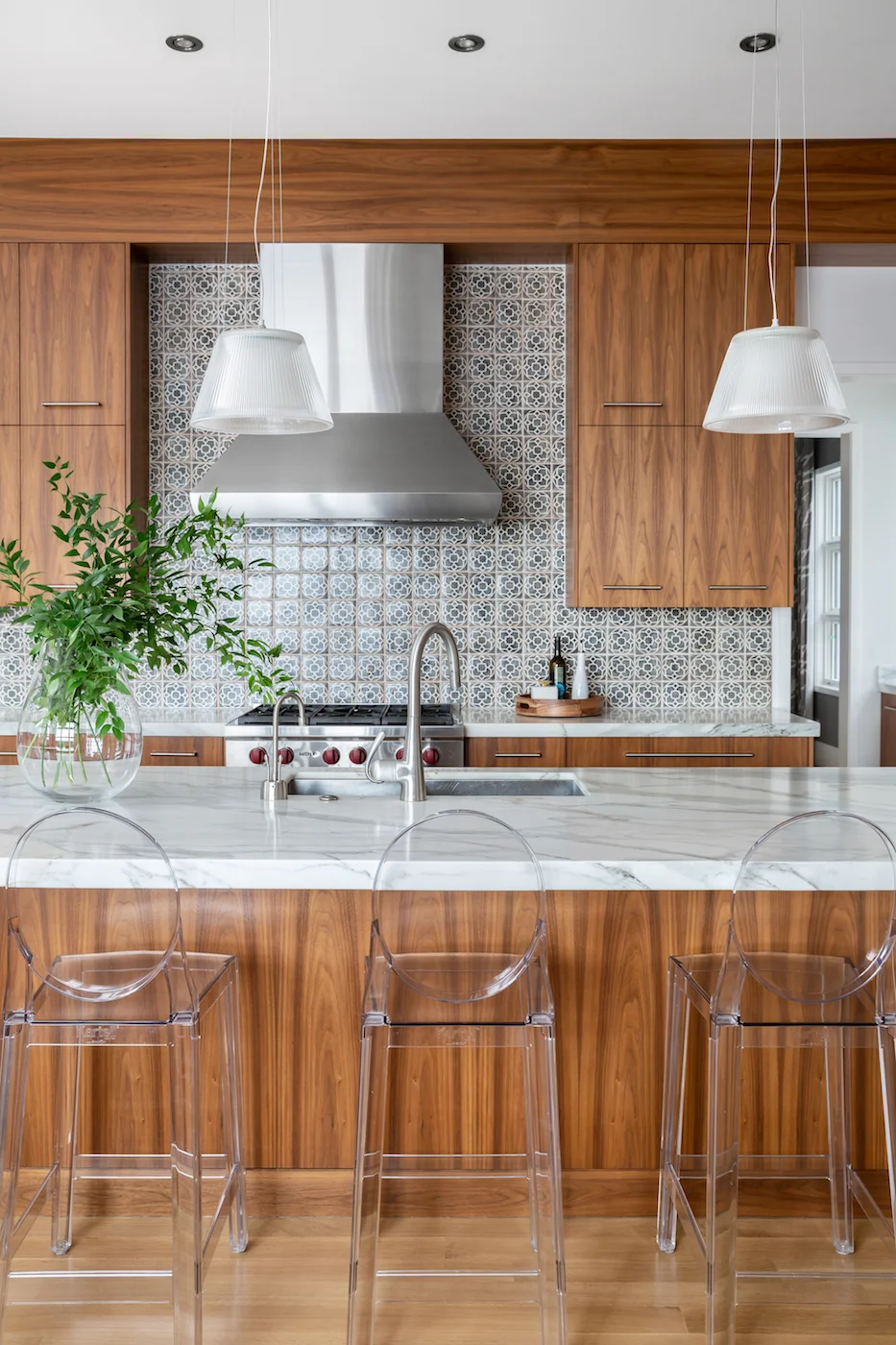 The kitchen, with walnut cabinetry, louis ghost counter stools, handmade ceramic tile backsplash and white marble waterfall countertop from an Elbow Park Residence, Interior Design by Calgary Design Studio: Nyla Free Designs, Photography: Phil Crozi