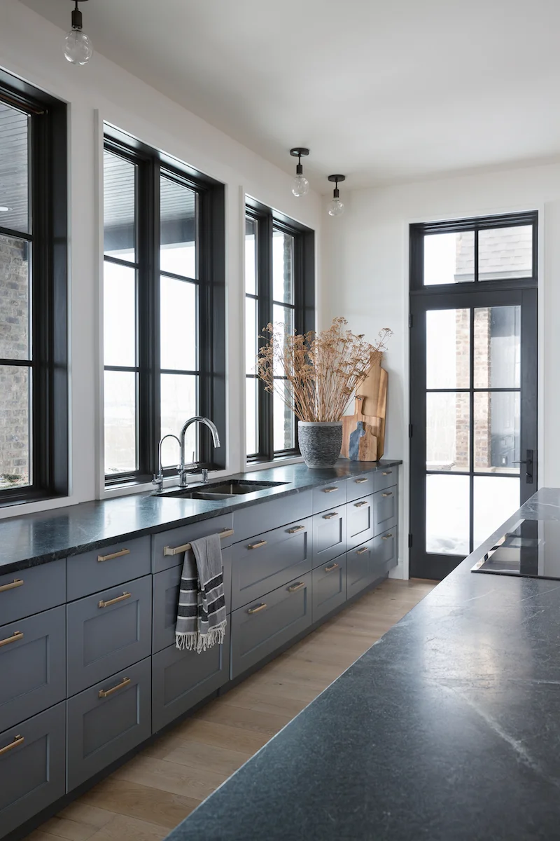 The kitchen with cooktop in island countertop, and windows extending over the counter from a Rural Alberta Country House, Interior Design by Calgary Design Studio Nyla Free Designs Inc, Architecture: Dejong Design Associates, Photography: Phil Crozier #calgaryinteriordesign #calgaryinteriordesigner #nylafreedesigns #kitcheninspirations #countryhouse