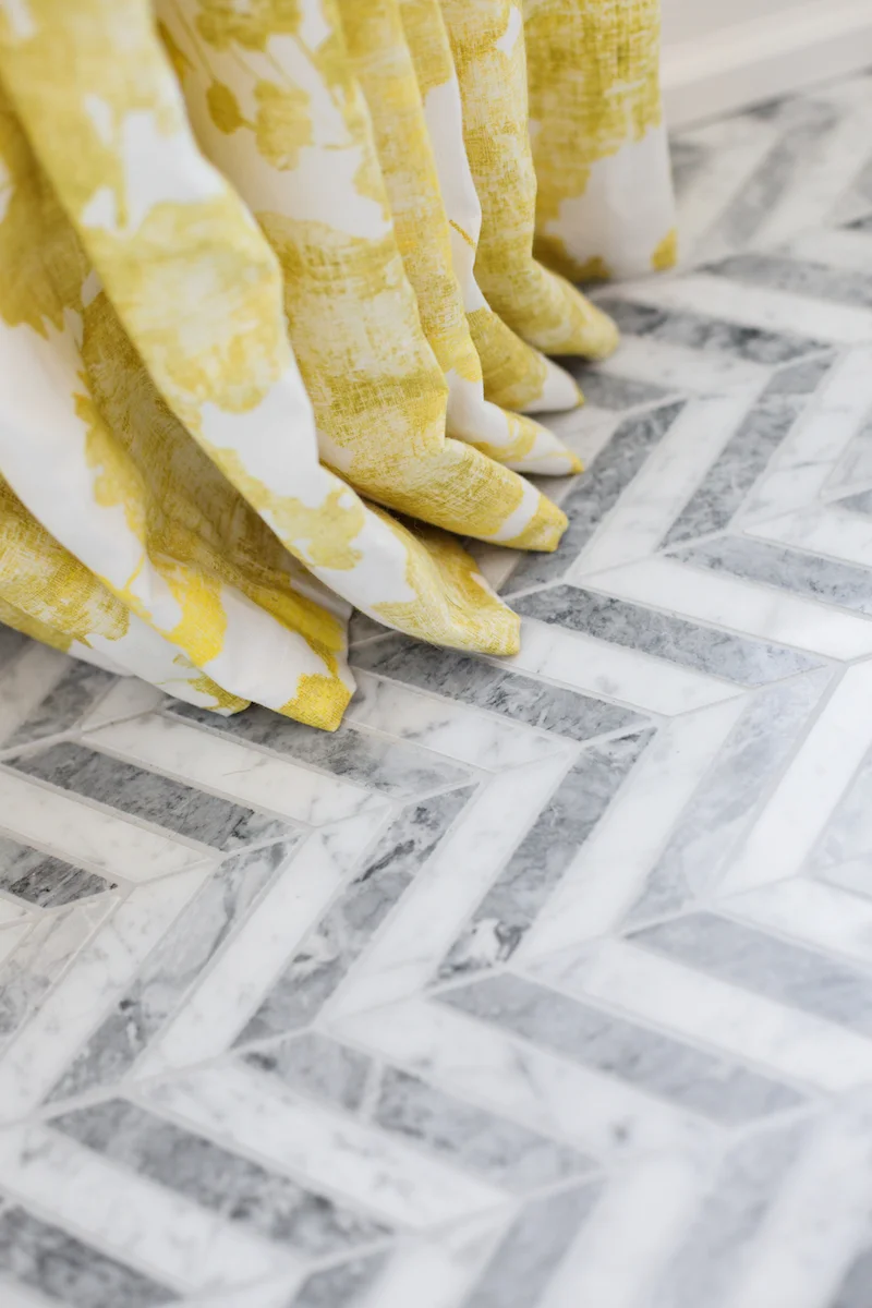 The neutral, light and airy master ensuite Bathroom with chevron marble tile floor, and yellow patterned drapery from a Rural Alberta Country House, Interior Design by Calgary Design Studio Nyla Free Designs Inc, Photography: Phil Crozier #calgaryinteriordesign #calgaryinteriordesigner #nylafreedesigns #masterensuiteinspirations #countryhouse