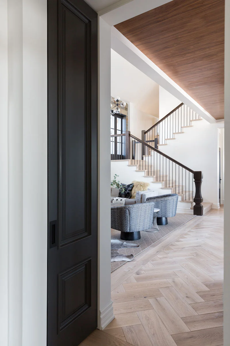 A light filled hallway looking into the living room with Herringbone Floors from a Rural Alberta Country House, Interior Design by Calgary Design Studio Nyla Free Designs Inc, Architecture: Dejong Design Associates, Photography: Phil Crozier #calgaryinteriordesign #calgaryinteriordesigner #nylafreedesigns #herringbonefloors #countryhouse