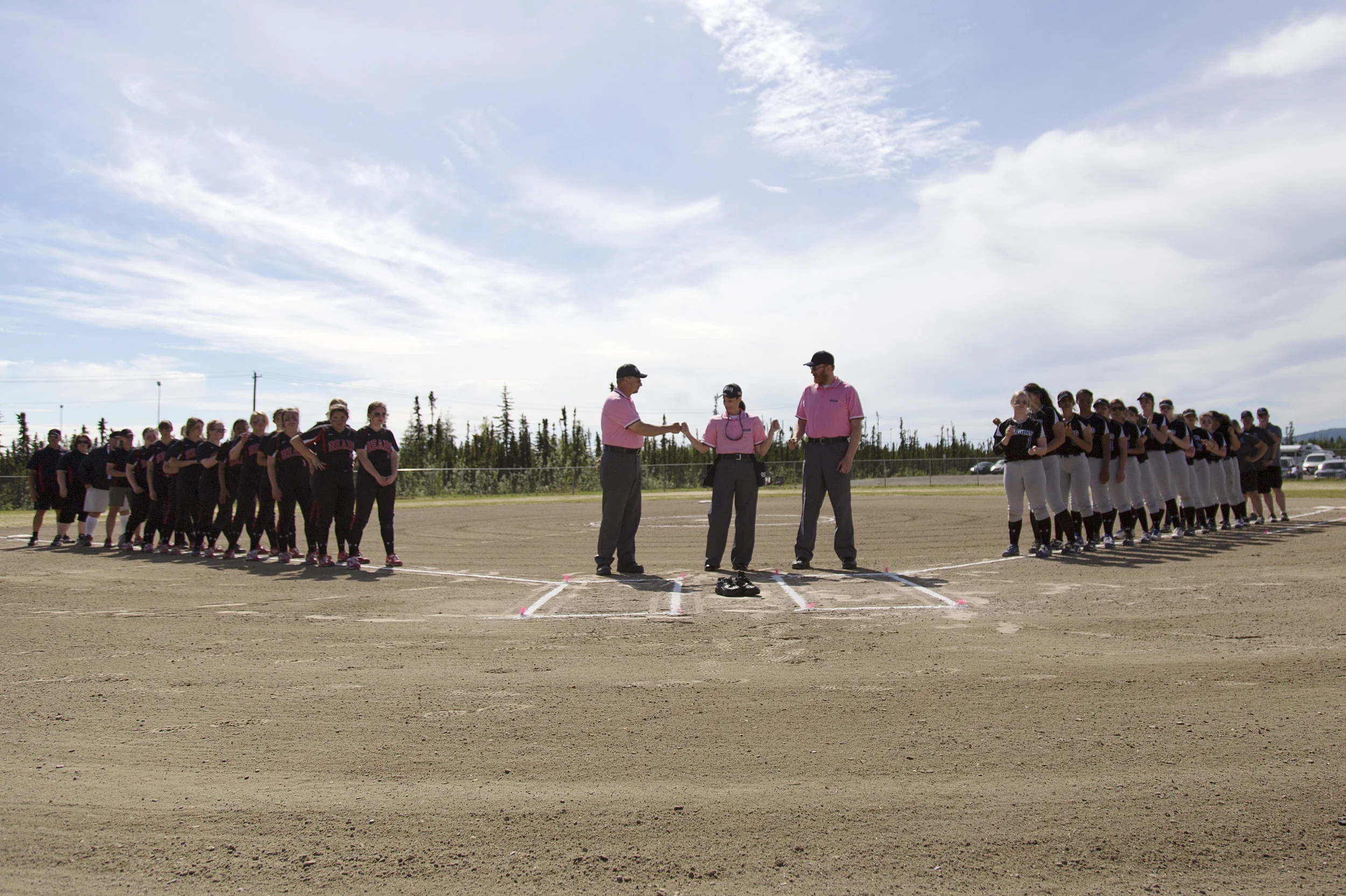 Juneau Douglas softball team and coaches (left) and the Thunder Mountain softball team and coaches (right) and umpires (center) line up before the start of the final game for the 2017 State Championship title on Saturday, June 3rd in the South Davis…