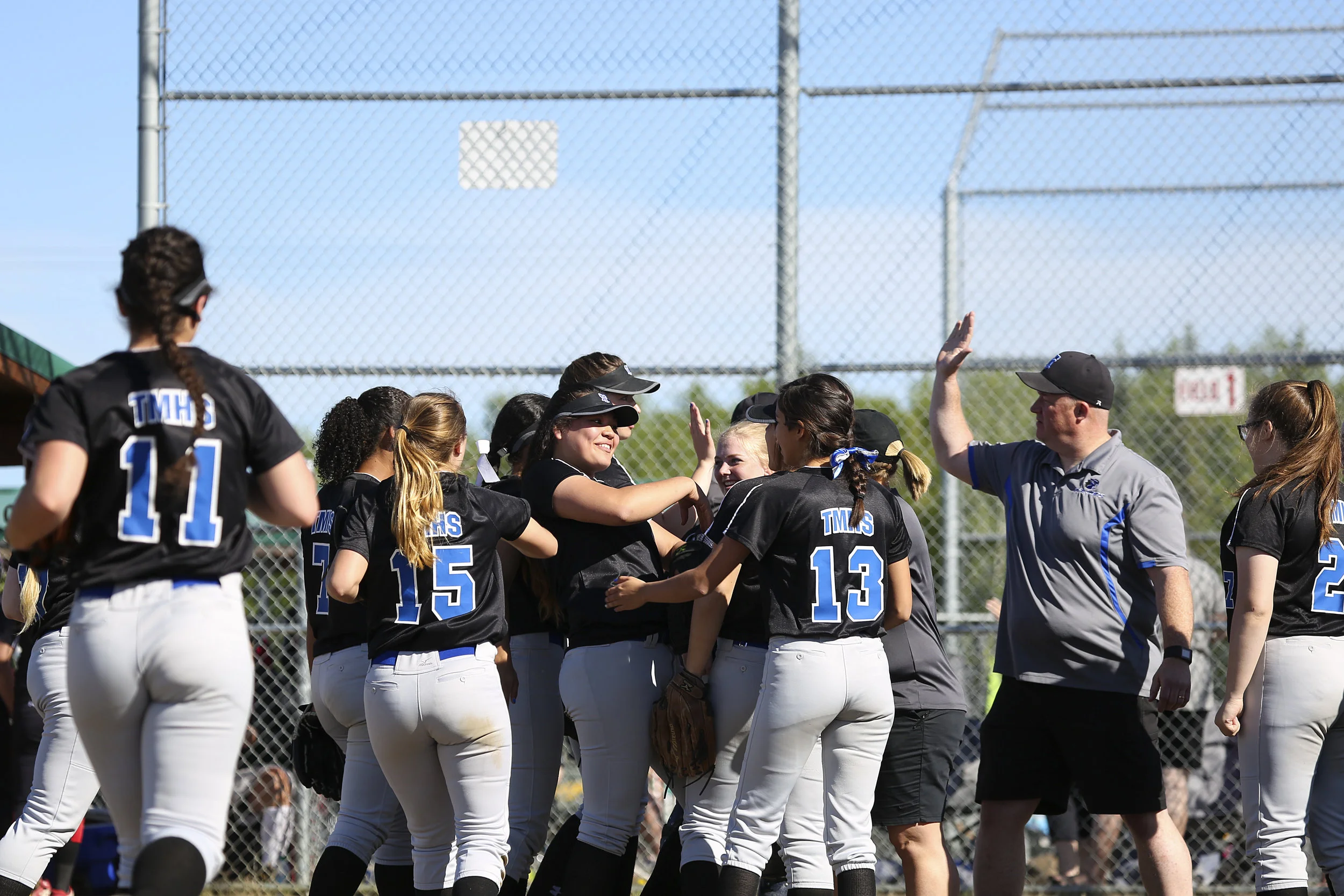 The Thunder Mountain softball team surrounds their pitcher, Nina Fenumiai (4) (center) on the field in celebration after the second inning with high fives and loud cheers in a game against Juneau Douglas on Saturday, June 3rd at the Softball State Championships in the South Davis Park Complex in Fairbanks, AK. Sarah Manriquez/ Juneau Empire