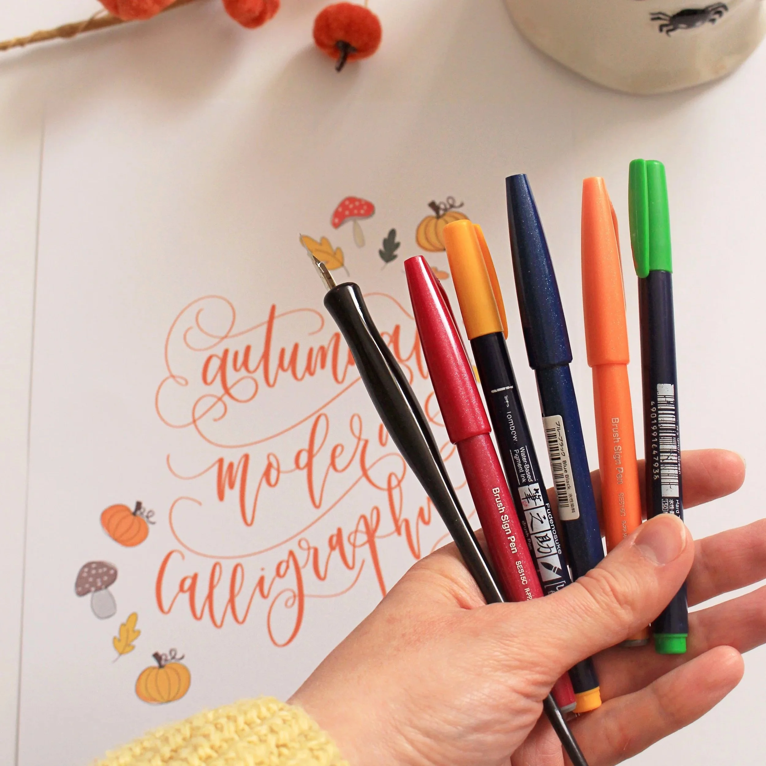 Brush pens, dip pens and modern calligraphy supplies arranged on a creative workspace.