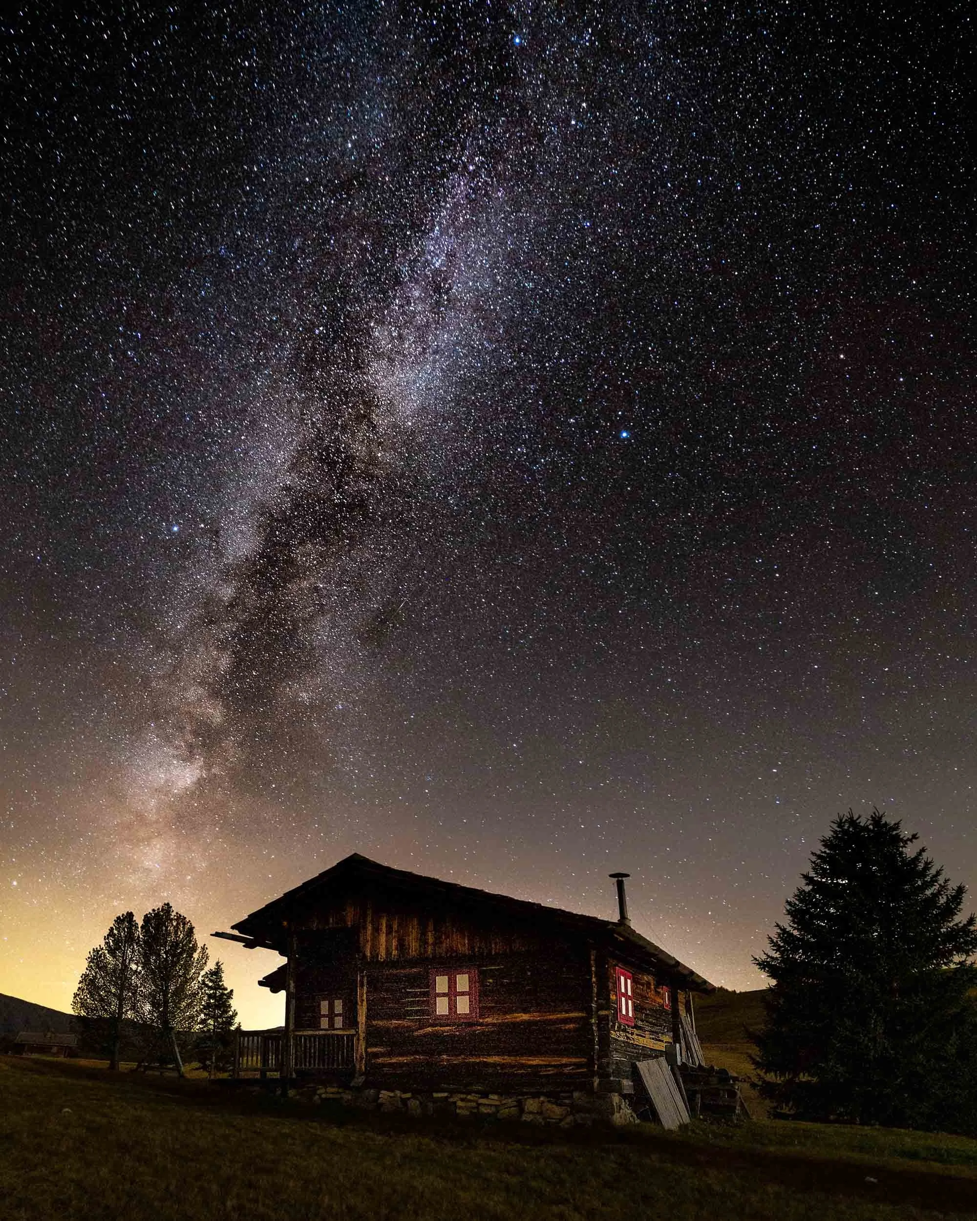 An alpine cabin on alpe di siusi under the milky way galaxy night sky.  