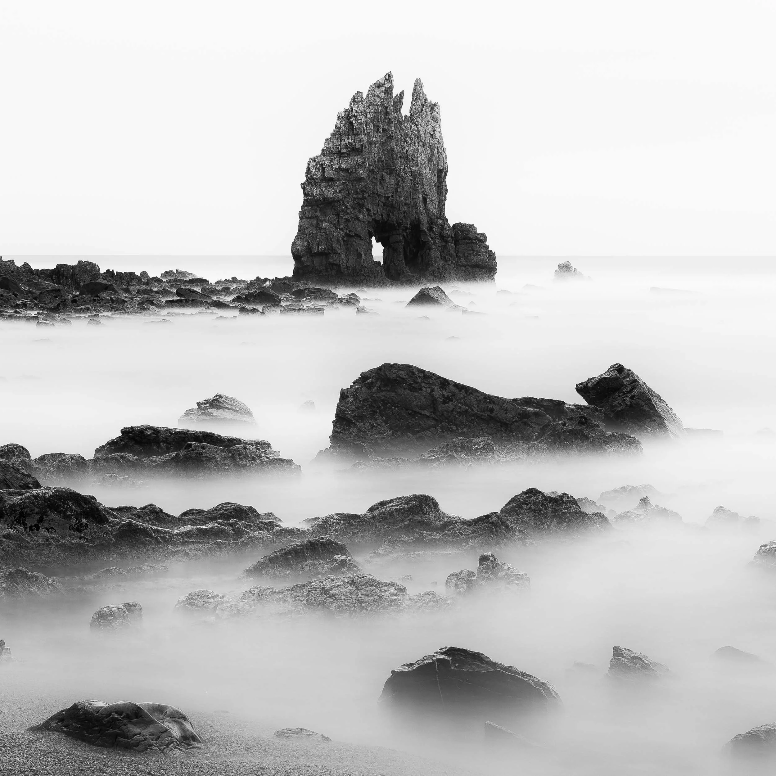 Black and white long exposure fine-art image of a sharp, spiky rock formation at the playa de portizuelo in the region of Asturias in northern Spain. 
