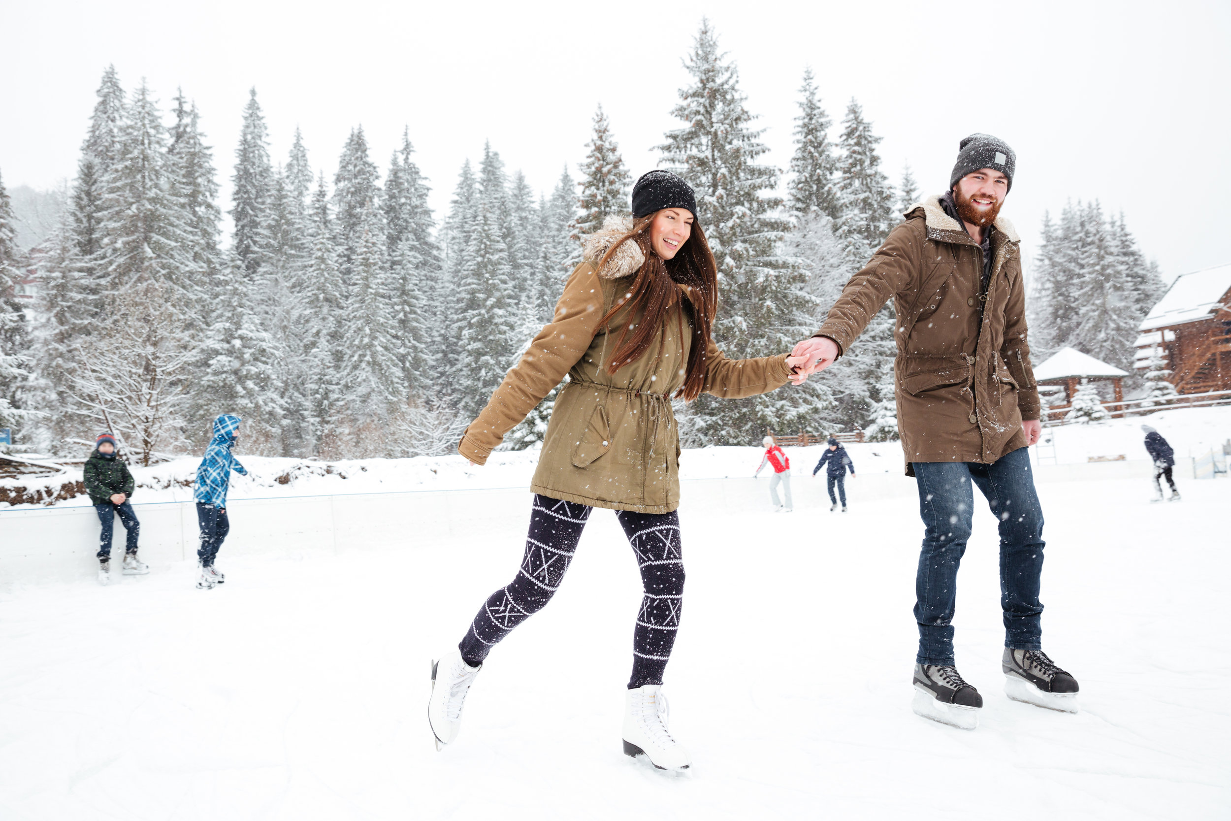 portrait-of-a-smiling-couple-ice-skating-outdoors-with-snow-on-background_BtWTx1Aro.jpg