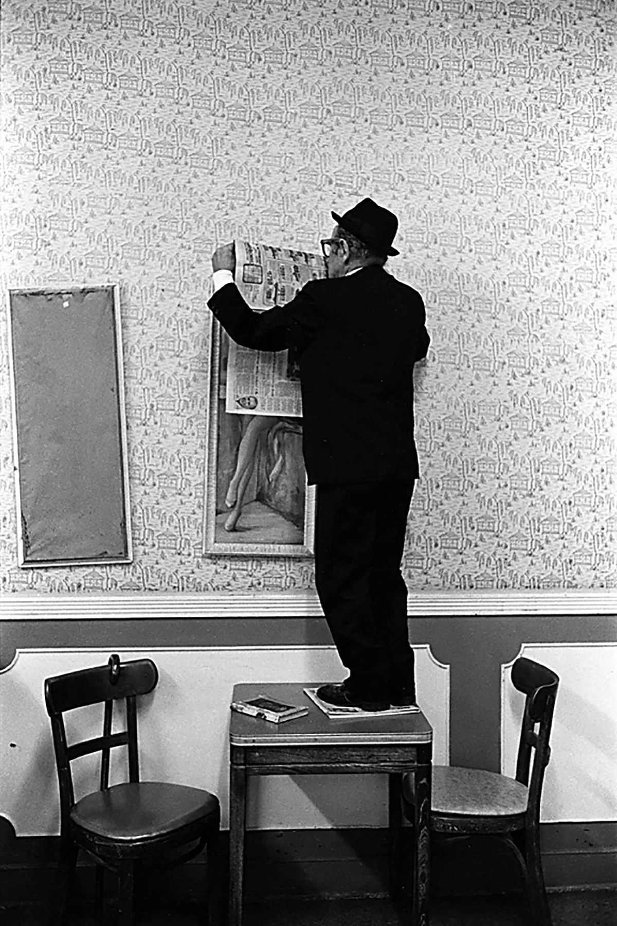 A man standing on table hanging up a poster