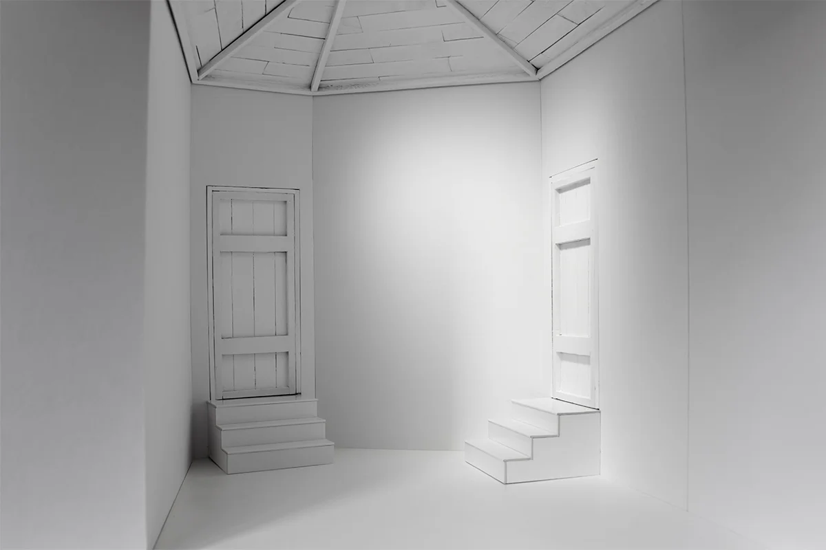 The interior of a model, showing a room with two sets of stairs each leading to a closed door