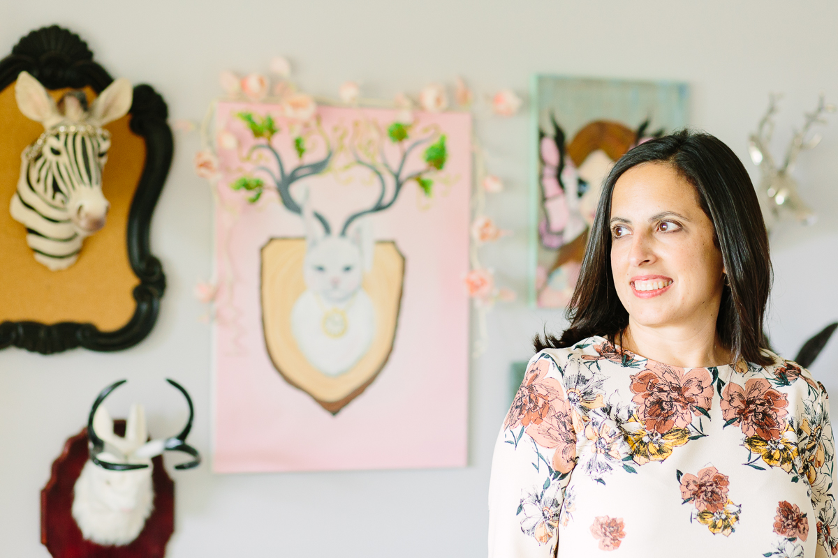 Rana at home in front of her whimsical paintings.