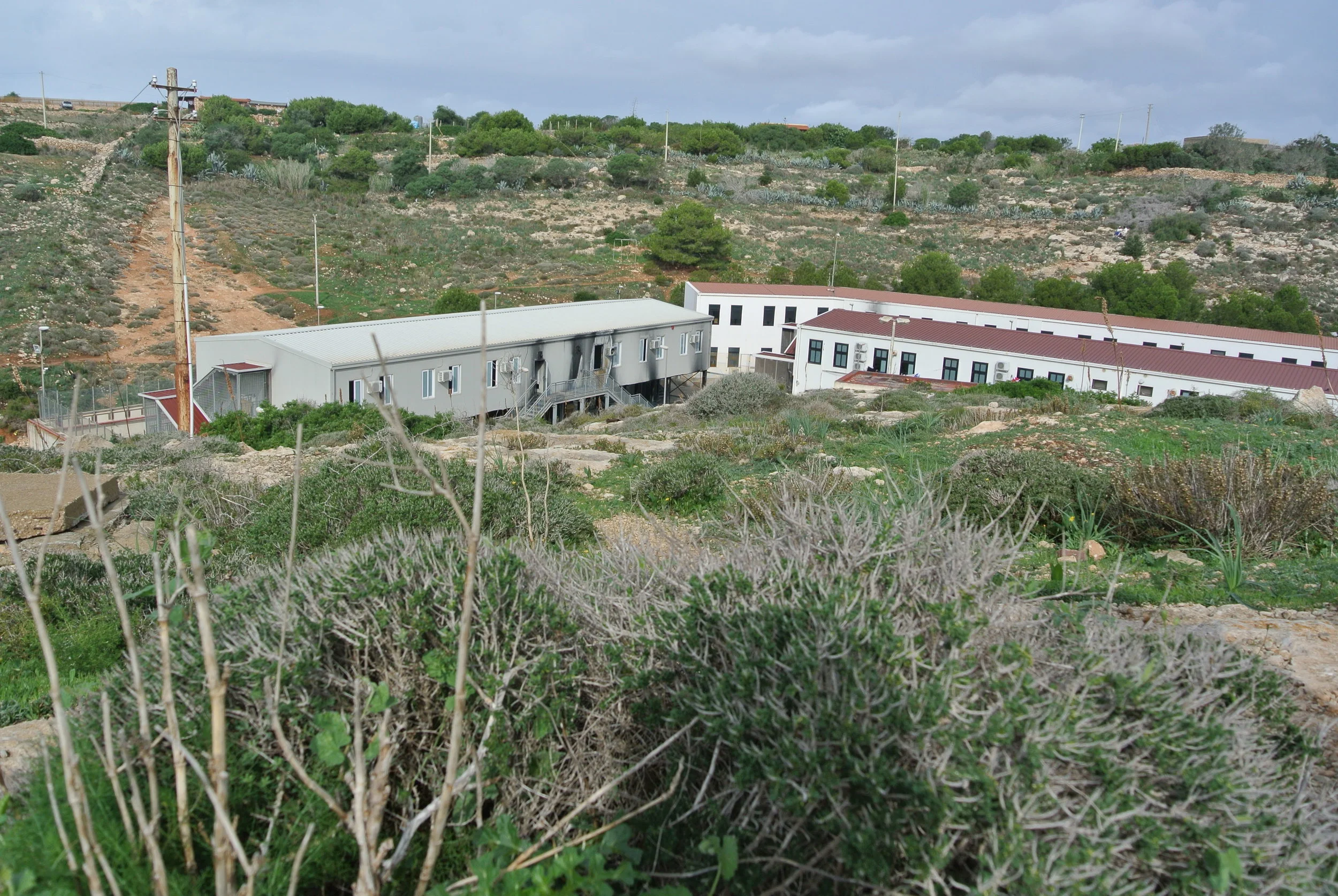  The Lampedusa hotspot; fire damage visible on building at left where migrants staged protest against the living conditions. November 2016. © Pamela Kerpius. 