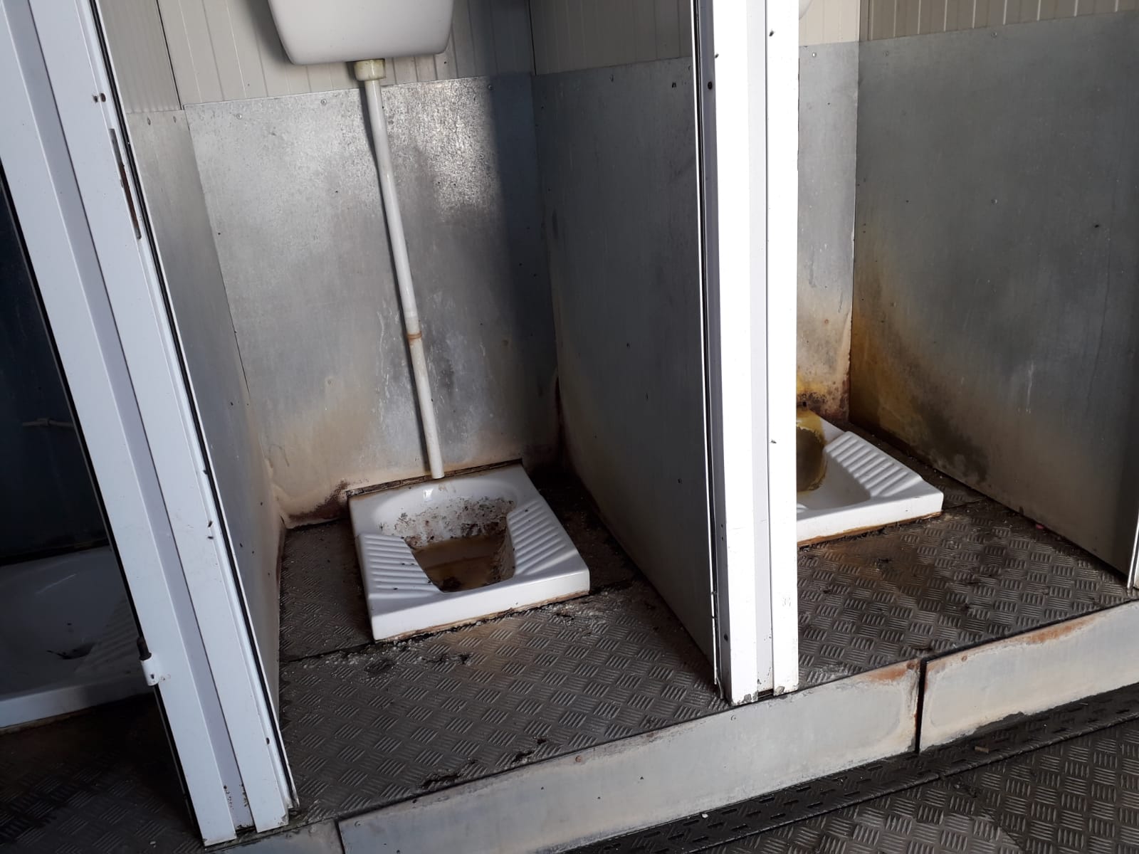   Bathroom stalls without doors and dirty toilets at the housing camp near Foggia, Italy. July, 2018. © Pamela Kerpius  