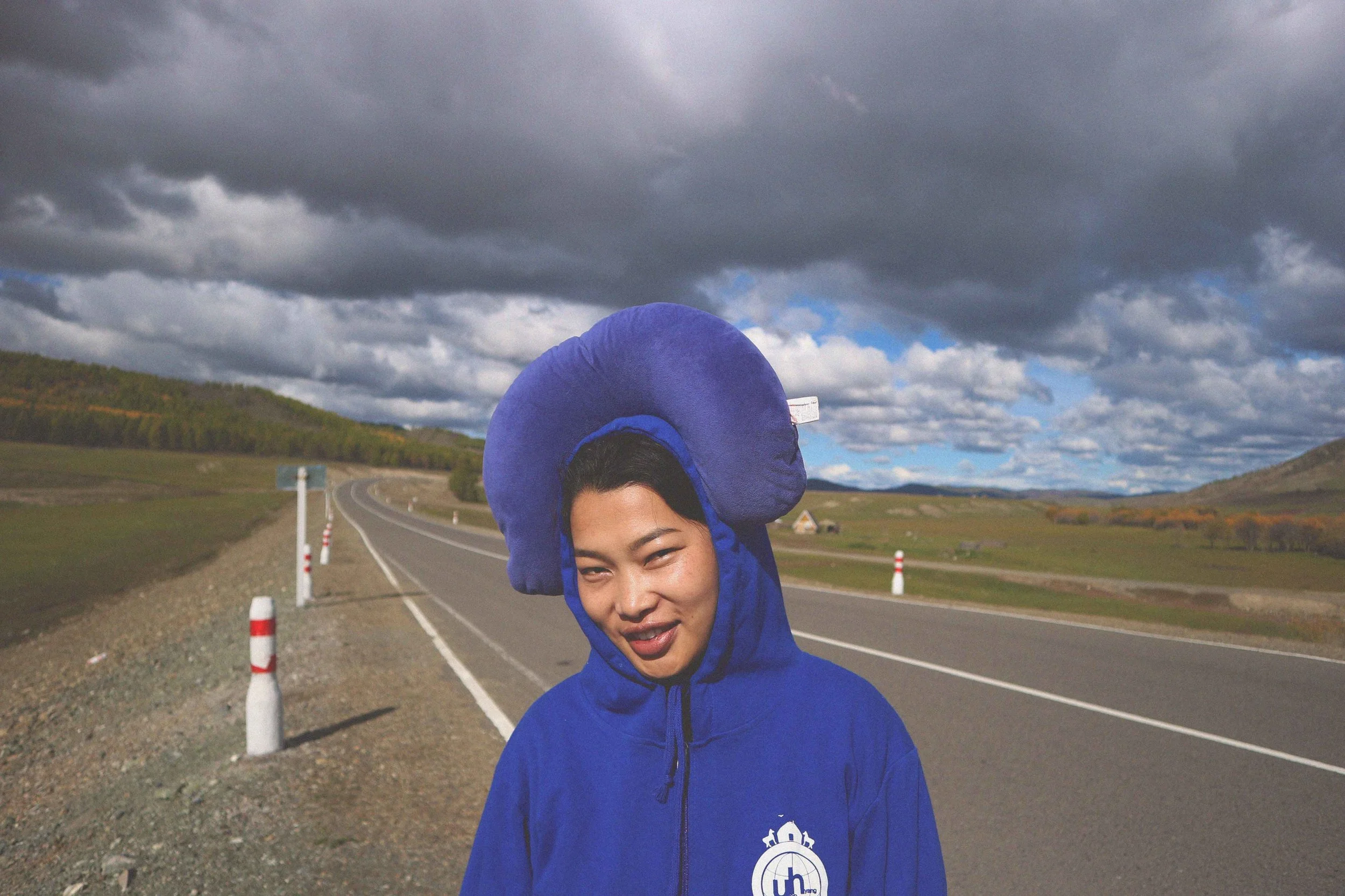 beautiful mongolian girl wears neck cushion on her head on a mongolia road trip tour guide