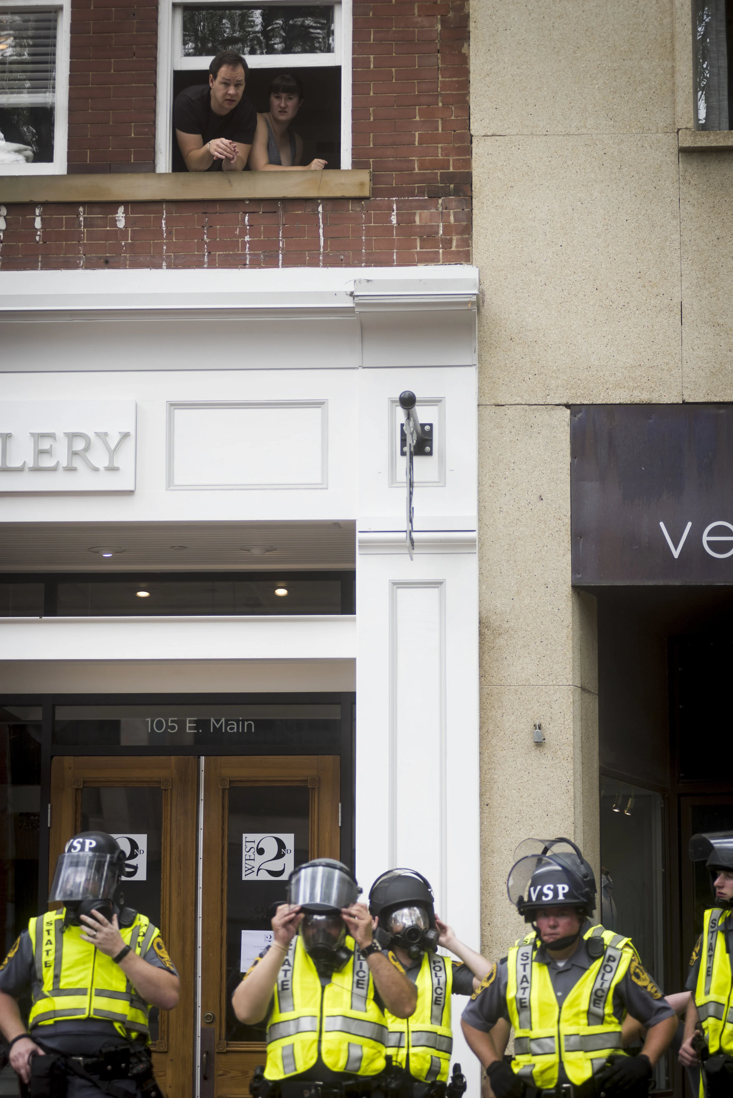  Locals peer down at police in riot gear in Charlottesville, VA, on August 12, 2017. 