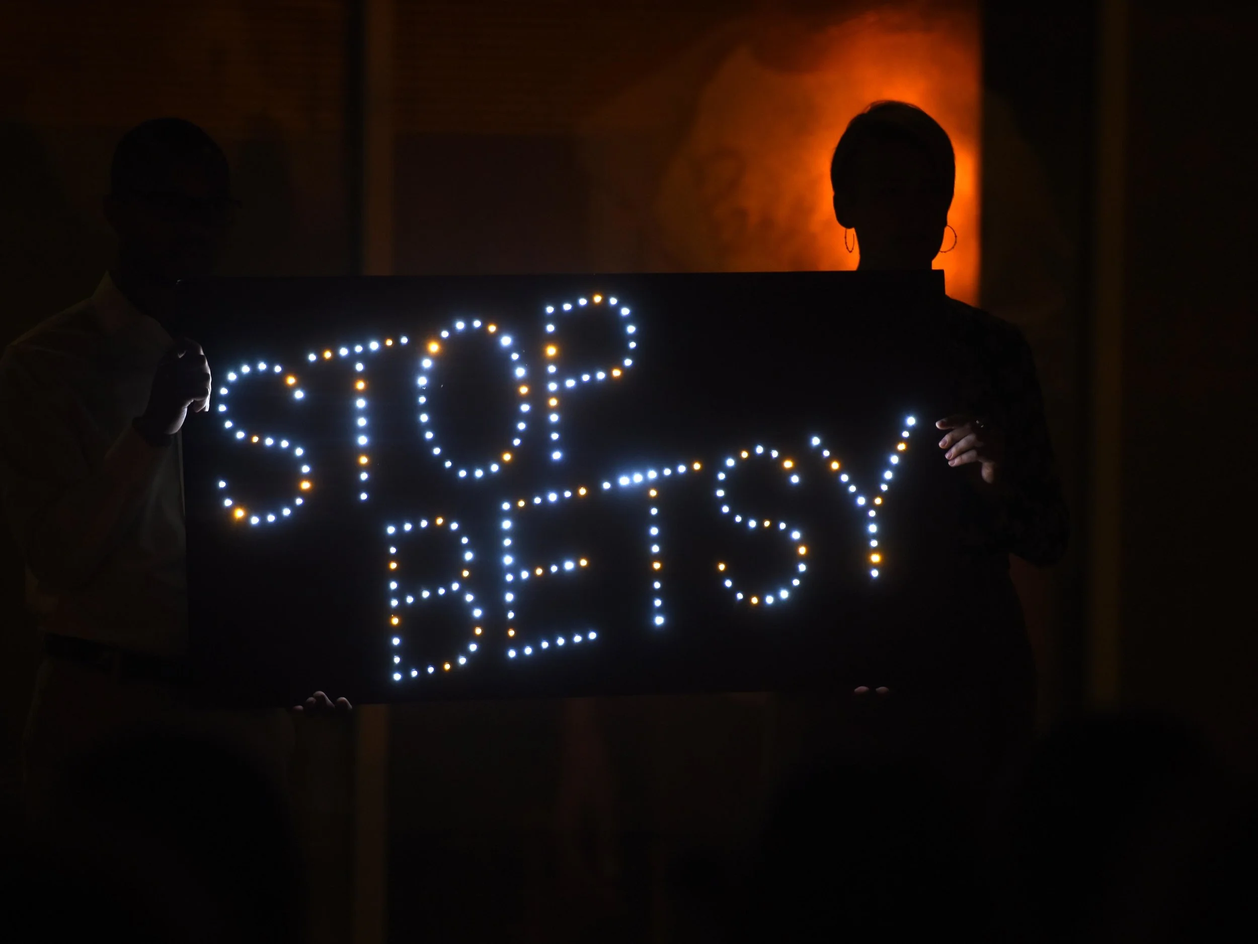  A demonstrator holds a light-up sign condemning Education Secretary Betsy DeVos' stance on Title IX enforcement during a candlelight vigil on October 19, 2017, outside the Department of Education in downtown D.C. 