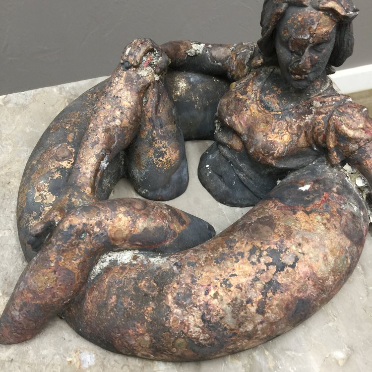 As it was found in the ashes. Severely oxidized, surface wrinkles, glass meted into the bronze in several areas, and the entire piece warped and bowed from the heat.