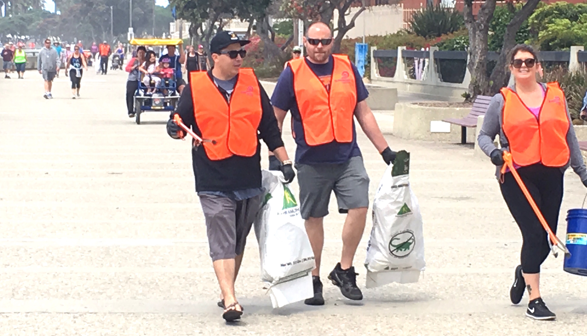 three VOLUNTEERS walk the promenade during a beach cleanup on june 24.
