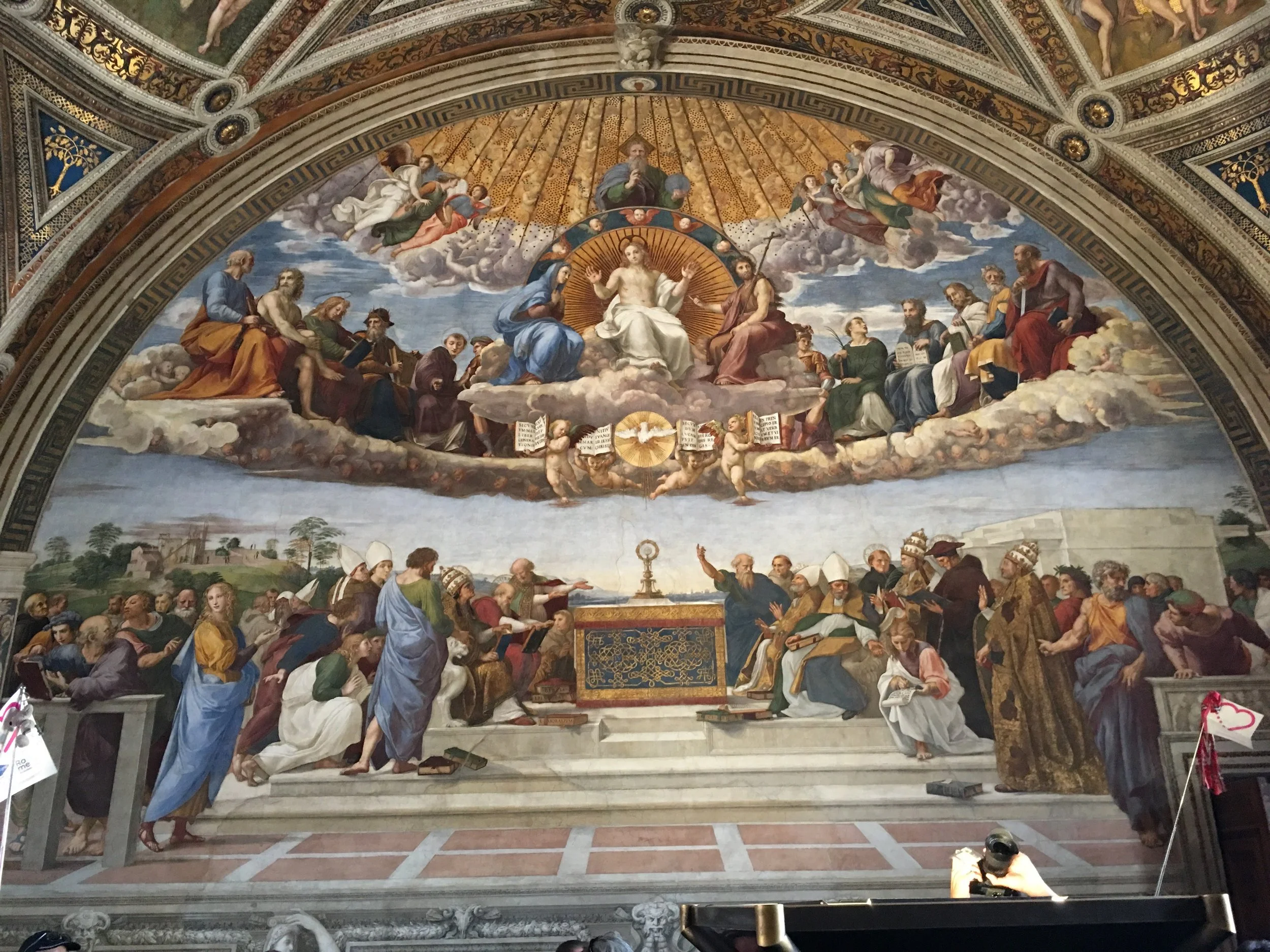 In Raphaels’ Disputation of the Holy Sacrament, located in the room Stanza Della Segnatura of Vatican City we see Jesus in the scene depicting both the heavens and earth. Jesus, bathed in light is located just below the Father God and above the burning light of the Holy Spirit. Forty days after his resurrection, according to the Gospel of Luke, Jesus ascends into heaven where he takes his place beside the Father God as the advocate for all of mankind.