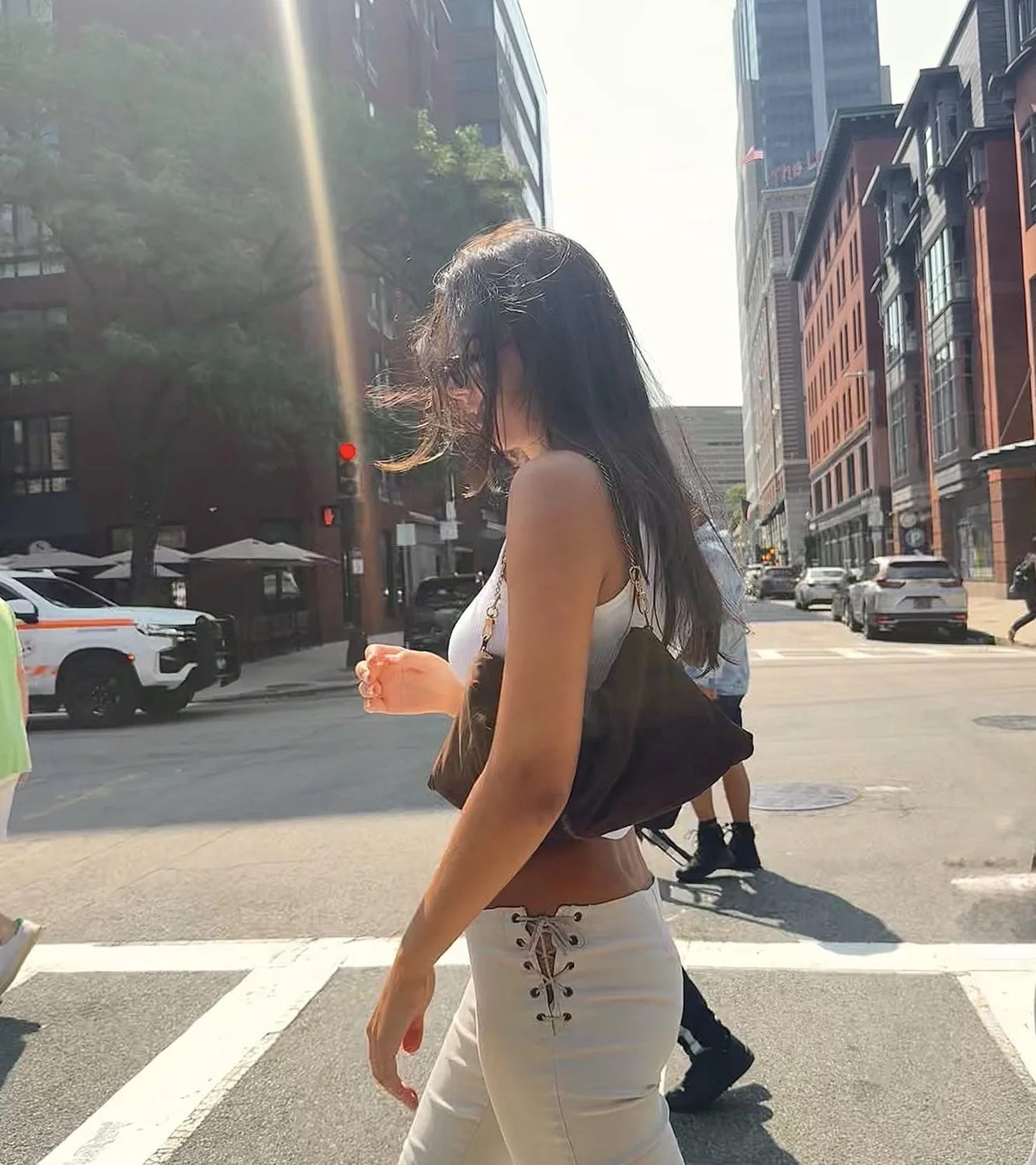 A woman carrying the brown JAQ purse while walking on a city street.