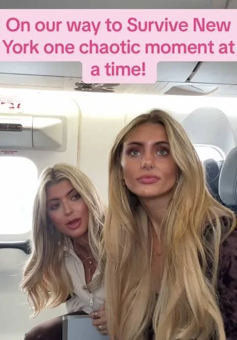 Two blonde women seated on a plane beneath pink text reading, “On our way to Survive New York one chaotic moment at a time!”
