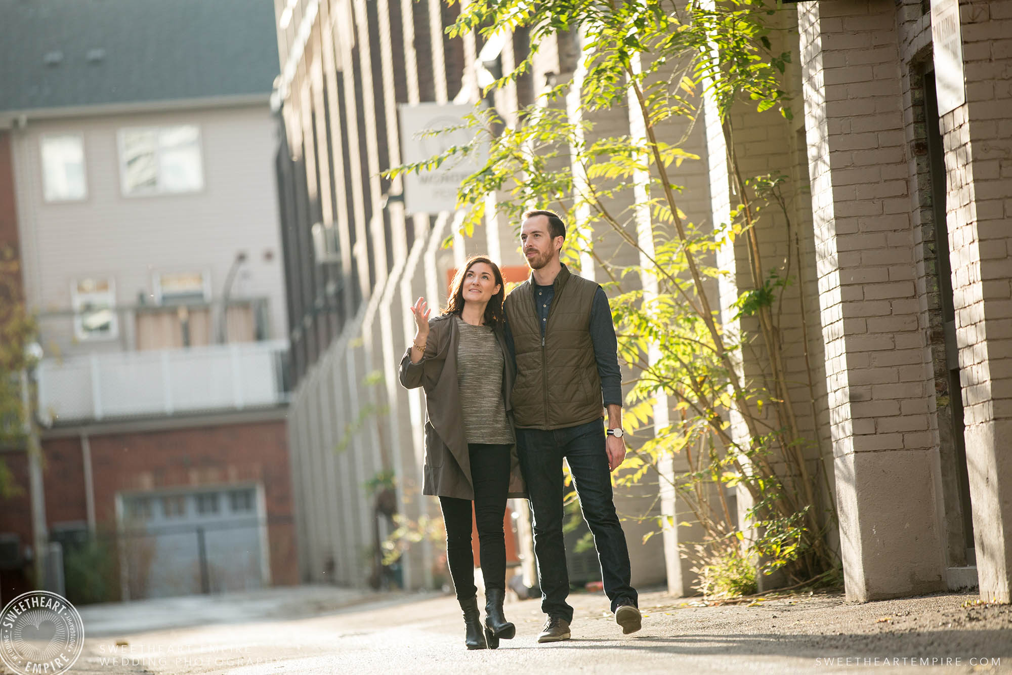 Couple holding hands walking in a sunny alleyway, Leslieville engagement photos