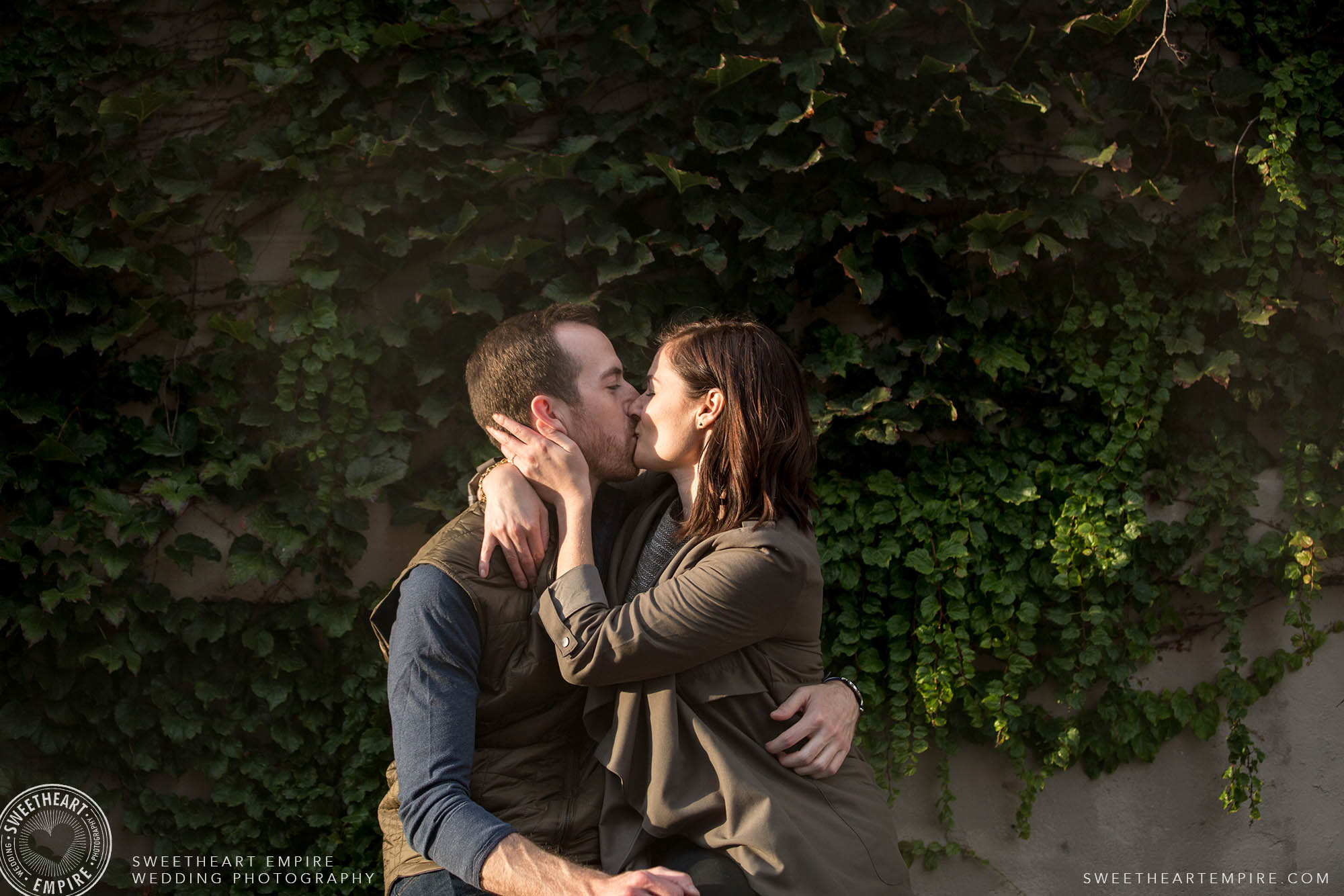 Couple kissing in the sun in front of an ivy wall, Leslieville engagement photos