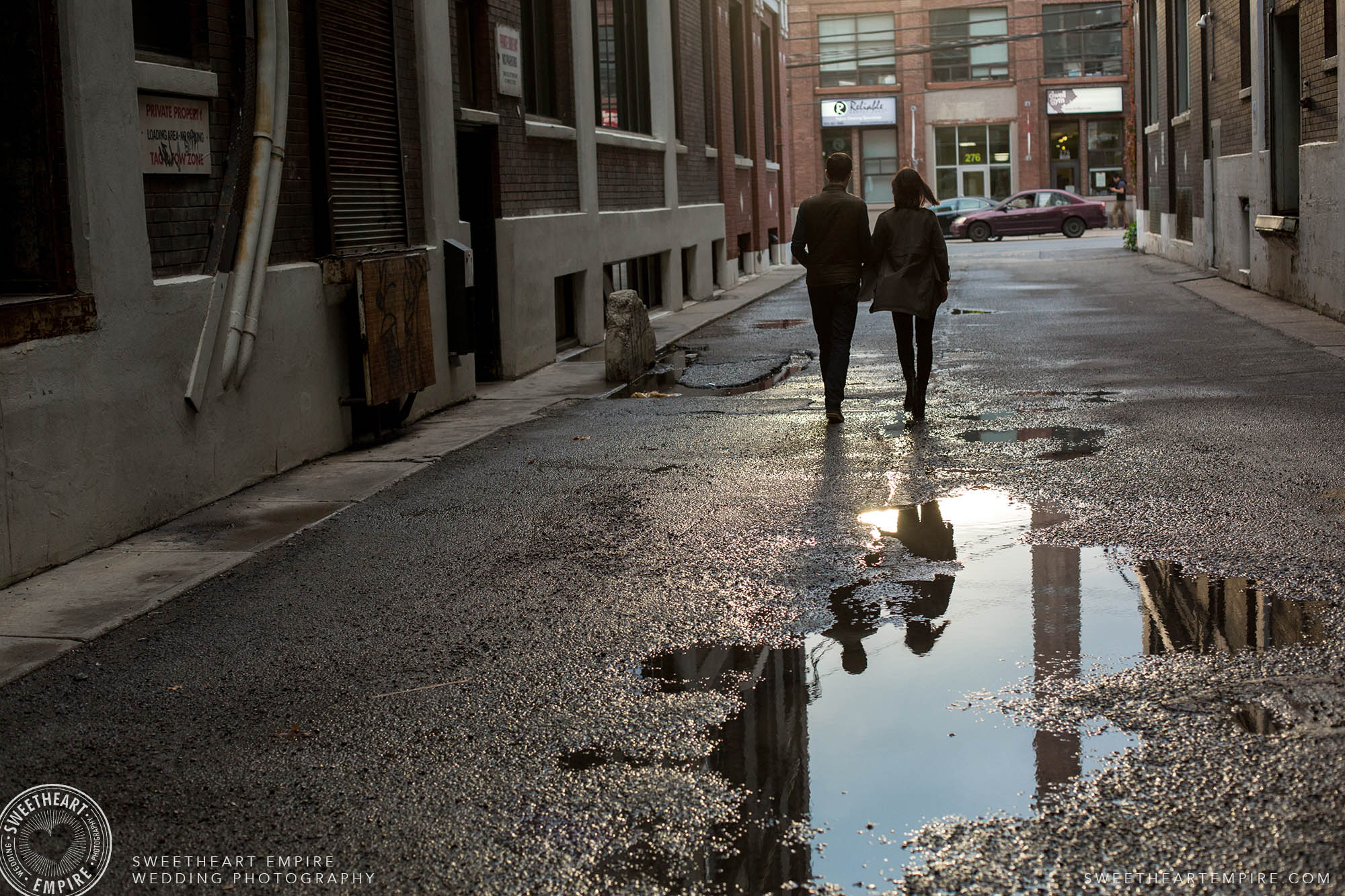 Reflection of a couple in a puddle as they walk away, Leslieville engagement photos