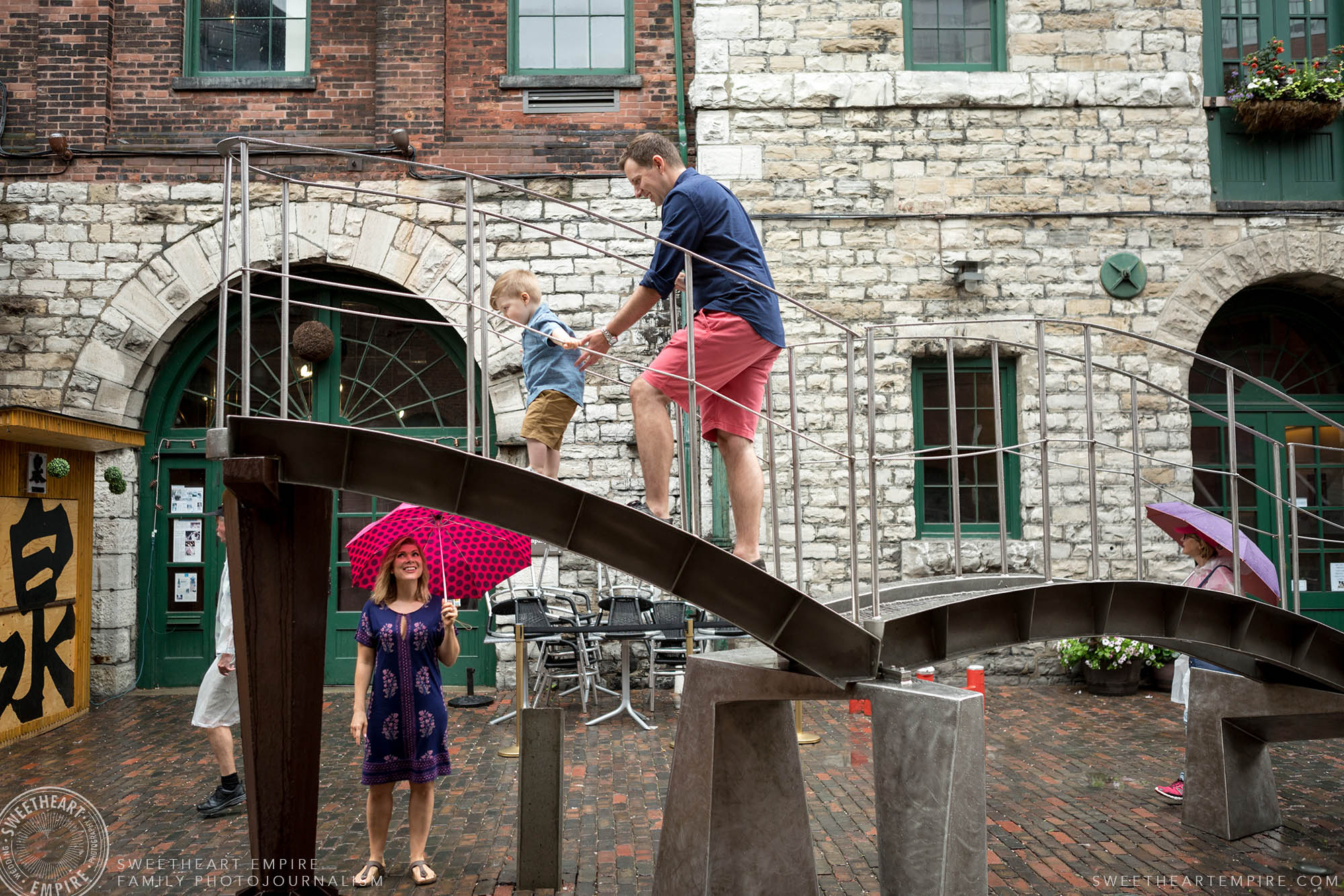 02_Father & toddler son climbing on sculptures in distillery district while concerned mom watches.jpg